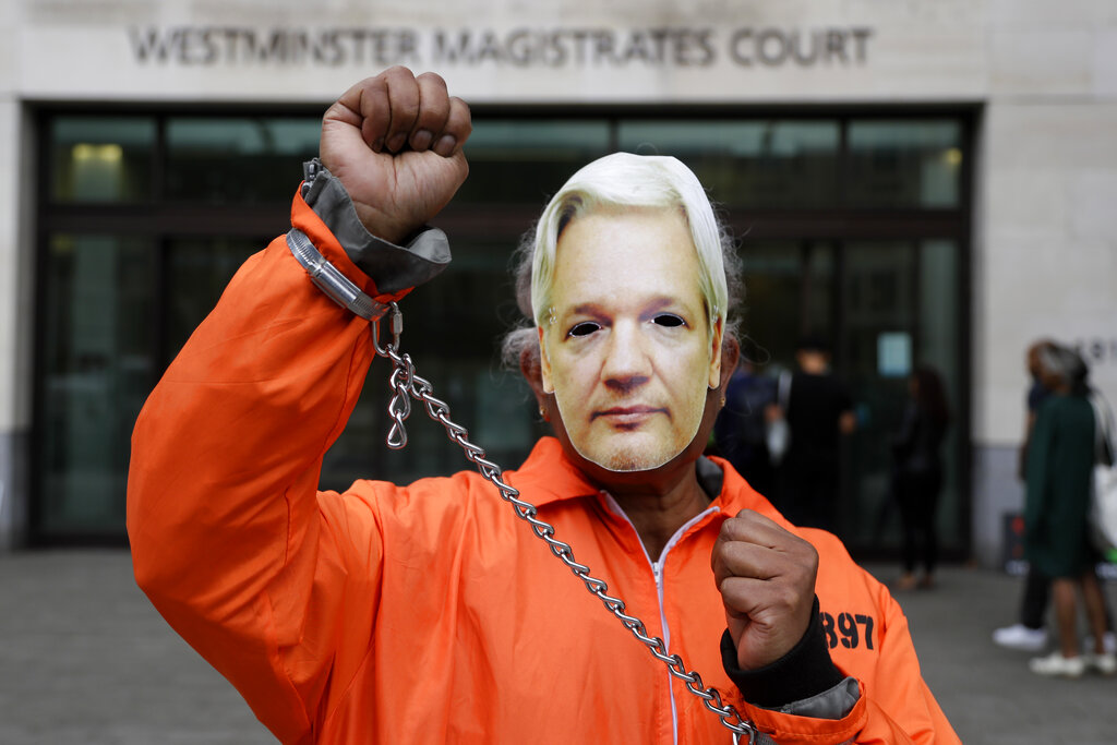 A demonstrator wears a mask and chains outside Westminster Magistrates Court in London, Friday, Aug. 14, 2020. A final procedural hearing in the Julian Assange extradition case will take place at the court Friday. (AP Photo/Kirsty Wigglesworth)