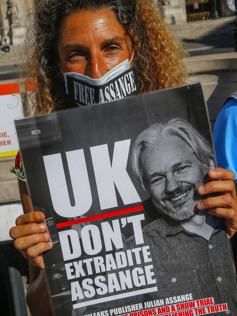 A demonstrator wearing acprotective face mask as precaution against the conoravirus stages a protest in Paris, Monday, Sept. 7, 2020. Lawyers for WikiLeaks founder Julian Assange and the U.S. government were squaring off in a London court on Monday at a high-stakes extradition case delayed by the coronavirus pandemic. (AP Photo/Michel Euler)