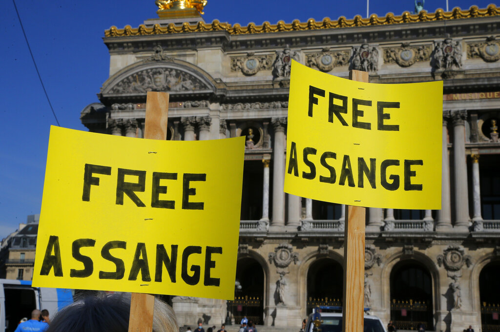 Demonstrators hold placards as they stage a protest in Paris, Monday, Sept. 7, 2020. Lawyers for WikiLeaks founder Julian Assange and the U.S. government were squaring off in a London court on Monday at a high-stakes extradition case delayed by the coronavirus pandemic. Opera in the background. (AP Photo/Michel Euler)