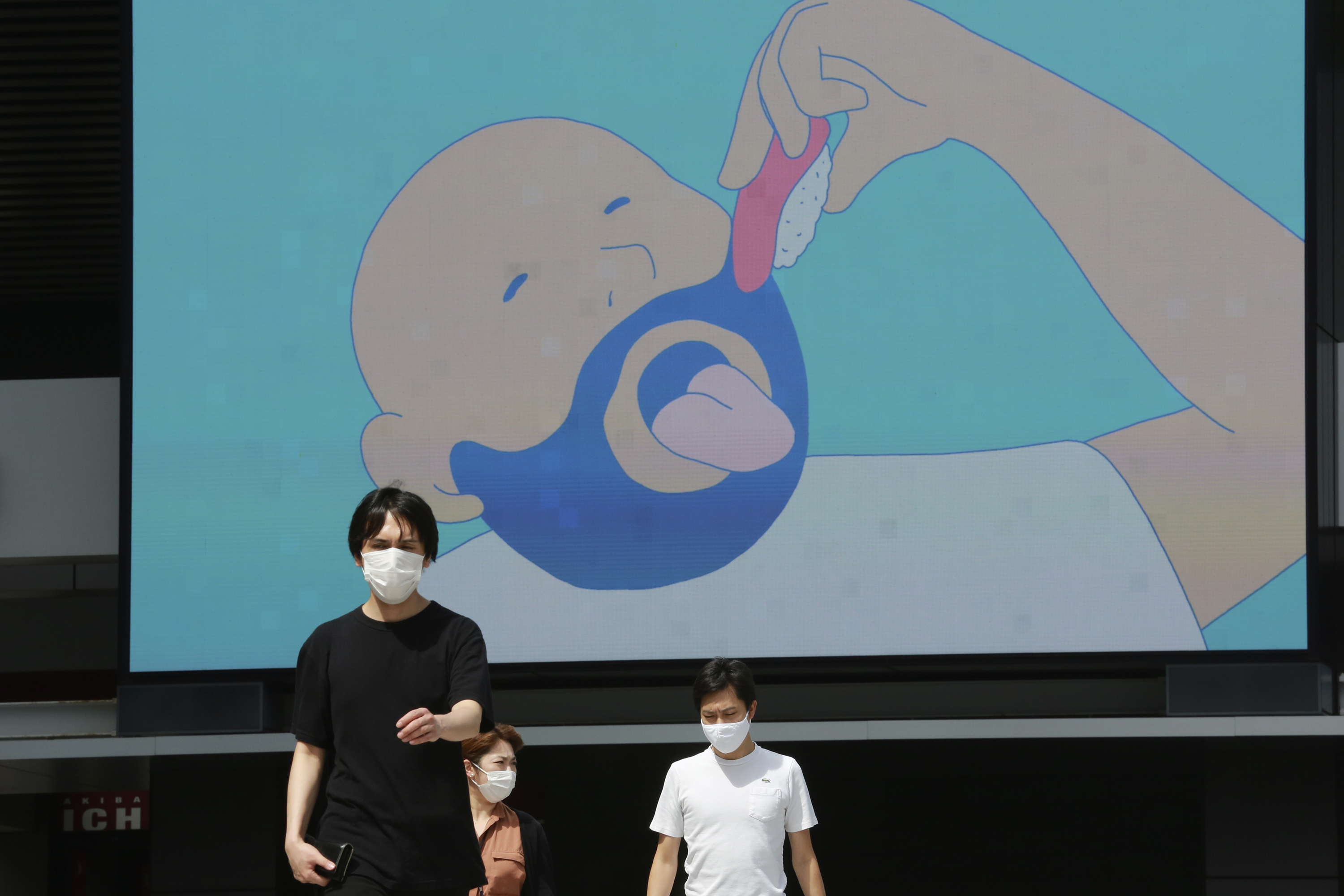 People wearing face masks to protect against the spread of the new coronavirus walk under a large screen in Tokyo, Monday, Sept. 7, 2020. (AP Photo/Koji Sasahara)