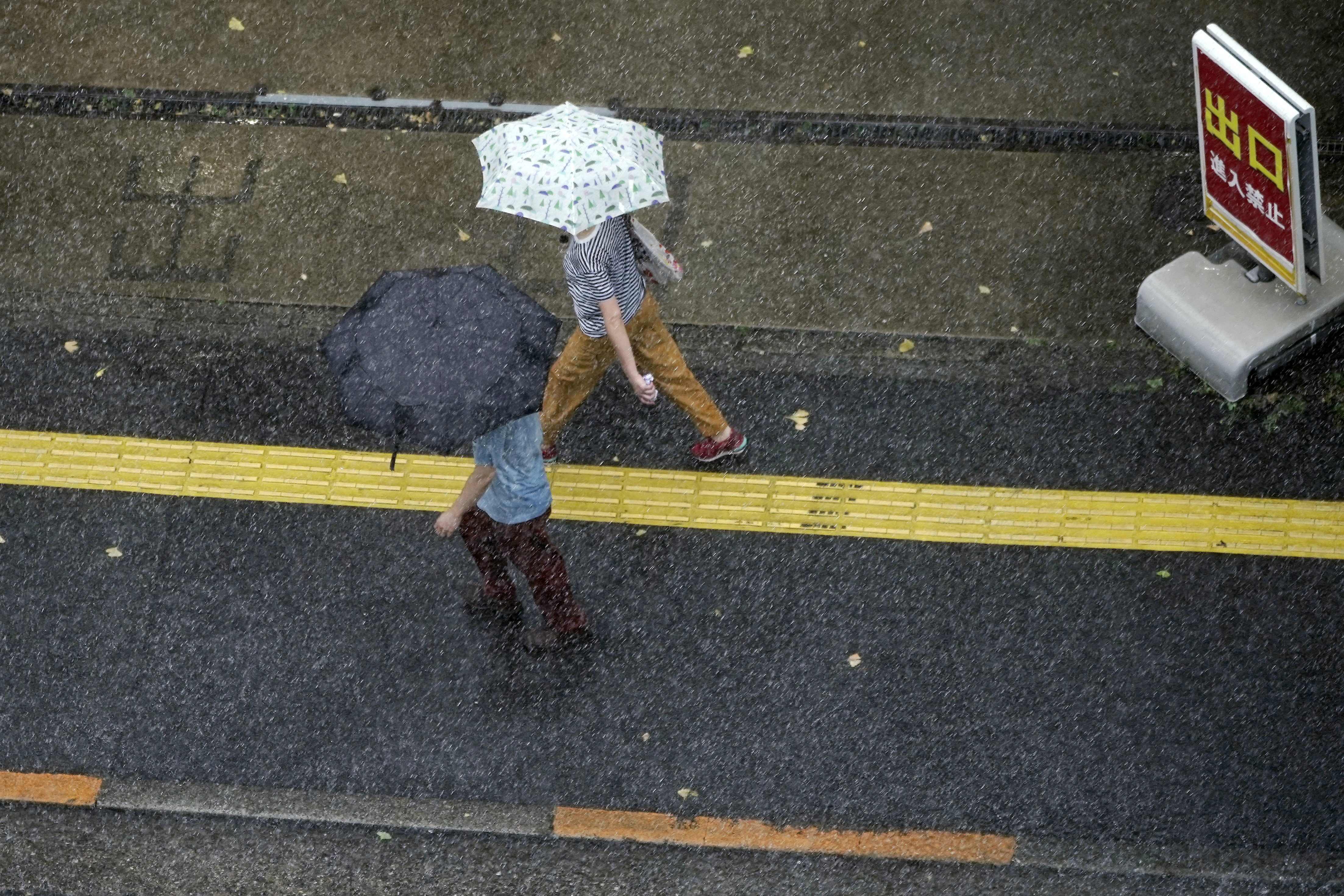 People walk in the heavy rain Monday, Sept. 7, 2020, in Tokyo. A powerful typhoon left people injured, damaged buildings, caused blackouts at nearly half a million homes and paralyzed traffic in southern Japanese islands before headed to South Korea. (AP Photo/Eugene Hoshiko)