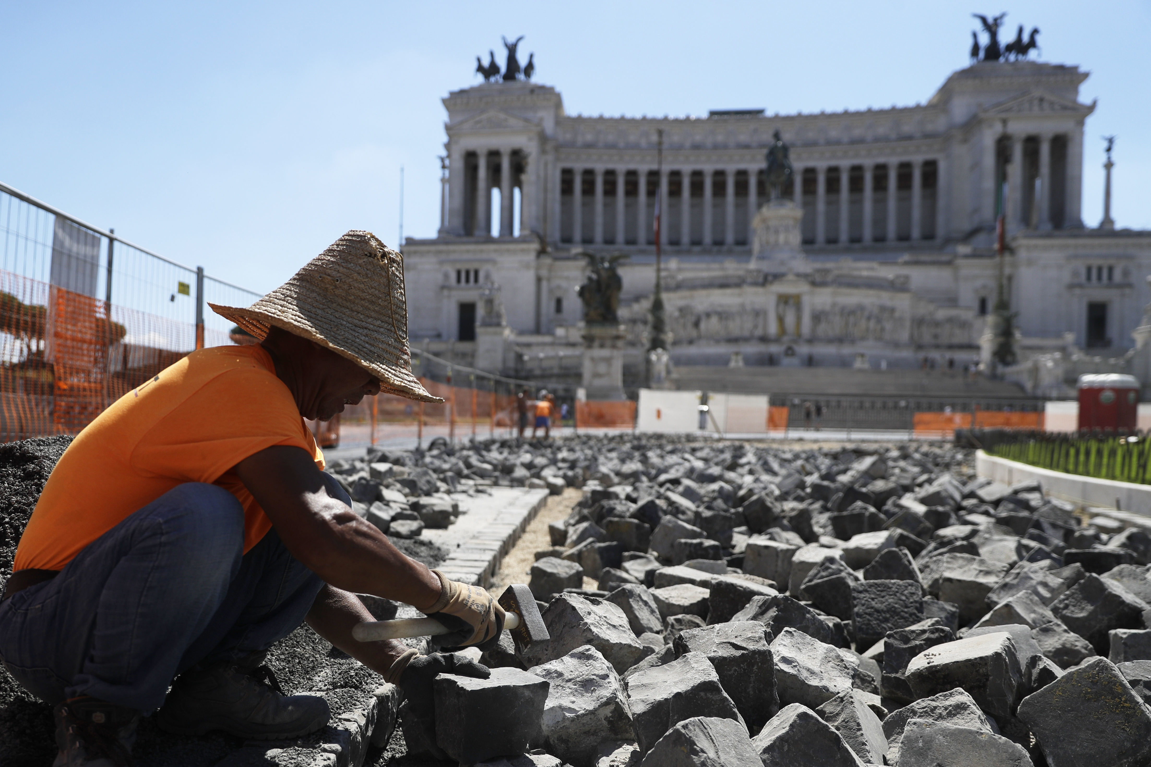 Construction worker Hu Shaoguang, of China, works on the remaking of the road surface with cobble stones in the central Venice Square in front of the Unknown Soldier monument in Rome, Monday, Sept. 7, 2020. (AP Photo/Gregorio Borgia)