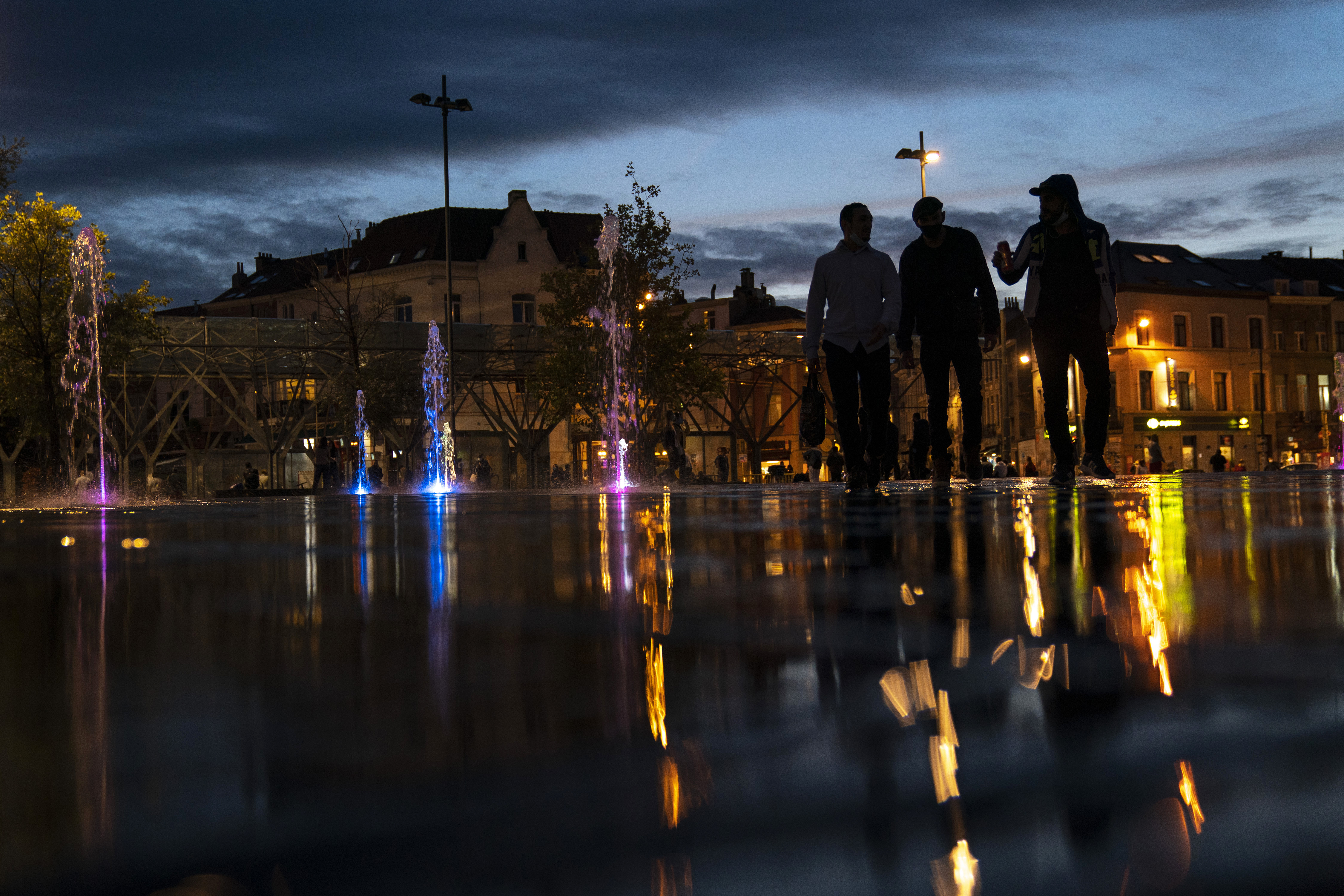People walk next to a public fountain at Flagey Square as the sun sets in Brussels, Monday, Sept. 7, 2020. (AP Photo/Francisco Seco)