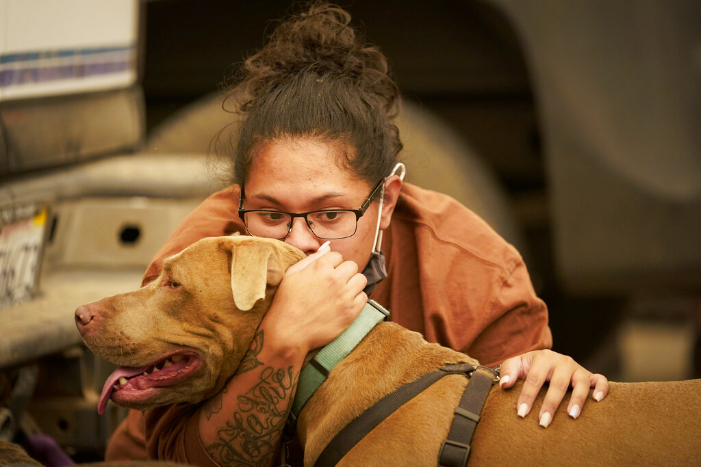 Inelva Gonzalez, of Armona, Calif. kisses her dog SayD in a marina, were campers were being held due to impassable roads, as the Creek Fire continues to burn Monday, Sept. 7, 2020, in Shaver Lake, Calif. (AP Photo/Marcio Jose Sanchez)