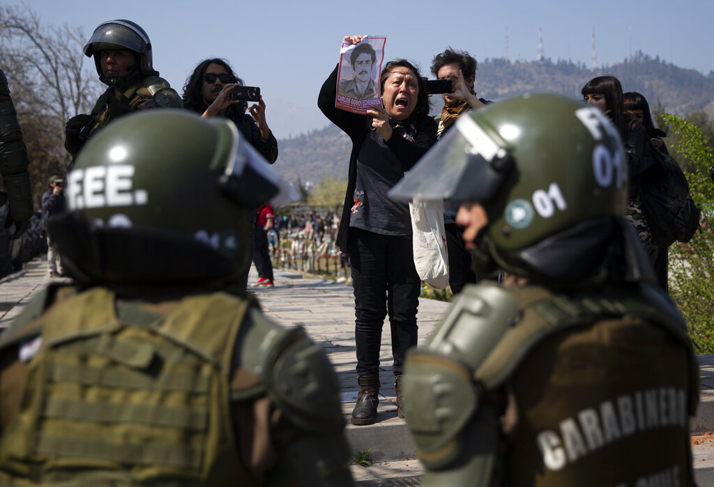 A woman shows a portrait of Carlos Godoy Echegoyen, who was executed by a police captain in 1985 during the dictatorship of Gen. Augusto Pinochet (1973-1990), during a protest at the historic monument 