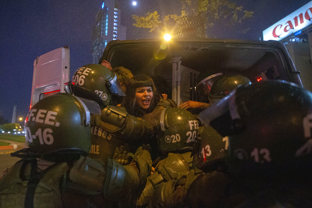 A woman is detained by police during a feminist protest marking the 46th anniversary of the military coup that ousted the late President Salvador Allende, in Santiago, Chile, Wednesday, Sept. 11, 2019. (AP Photo/Esteban Felix)