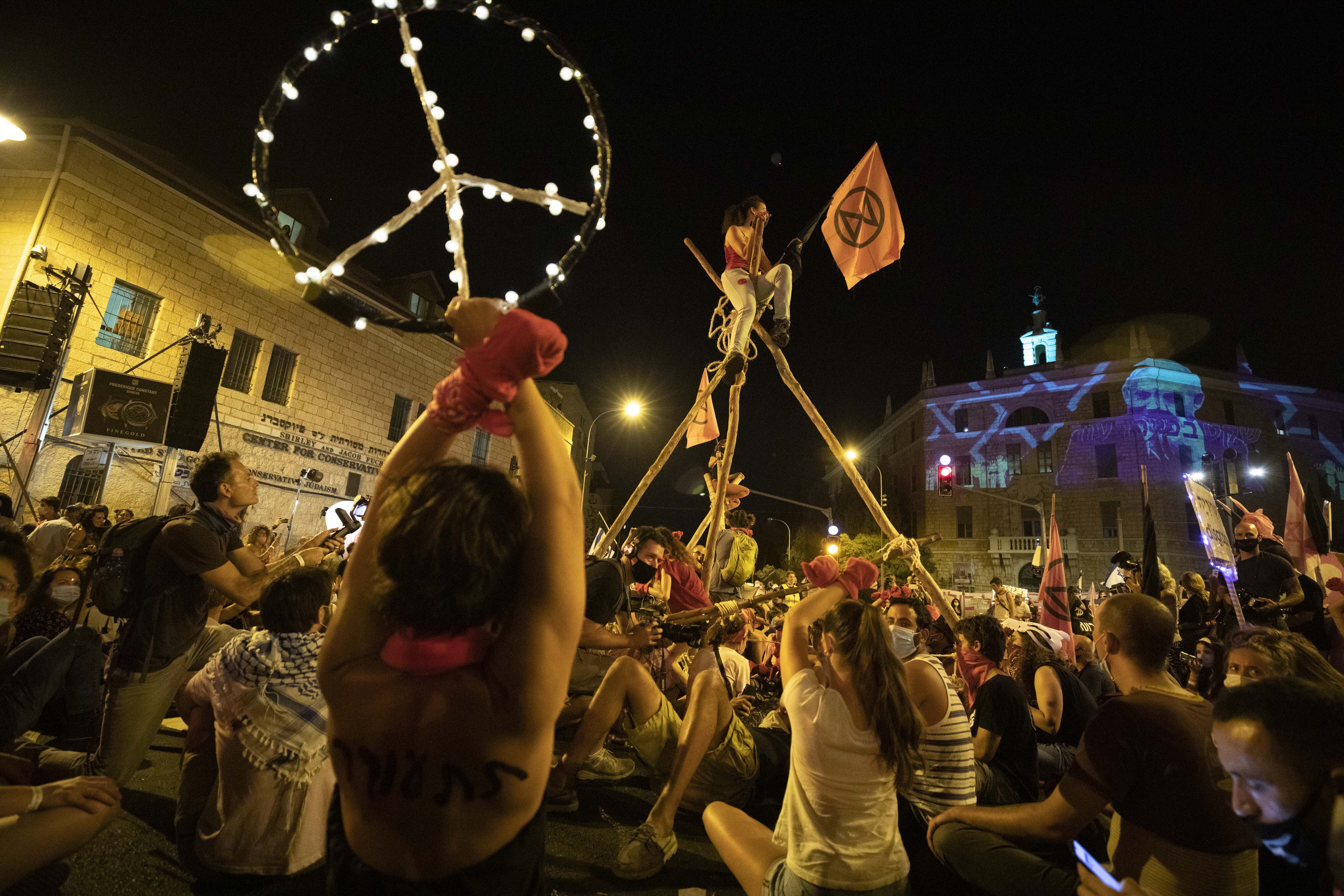 Protesters gather for a demonstration against Prime Minister Benjamin Netanyahu outside his official residence in Jerusalem, Saturday, Sept. 12, 2020, demanding he resign over his trial on corruption charges and what is widely seen as his mishandling of the coronavirus pandemic. (AP Photo/Sebastian Scheiner)