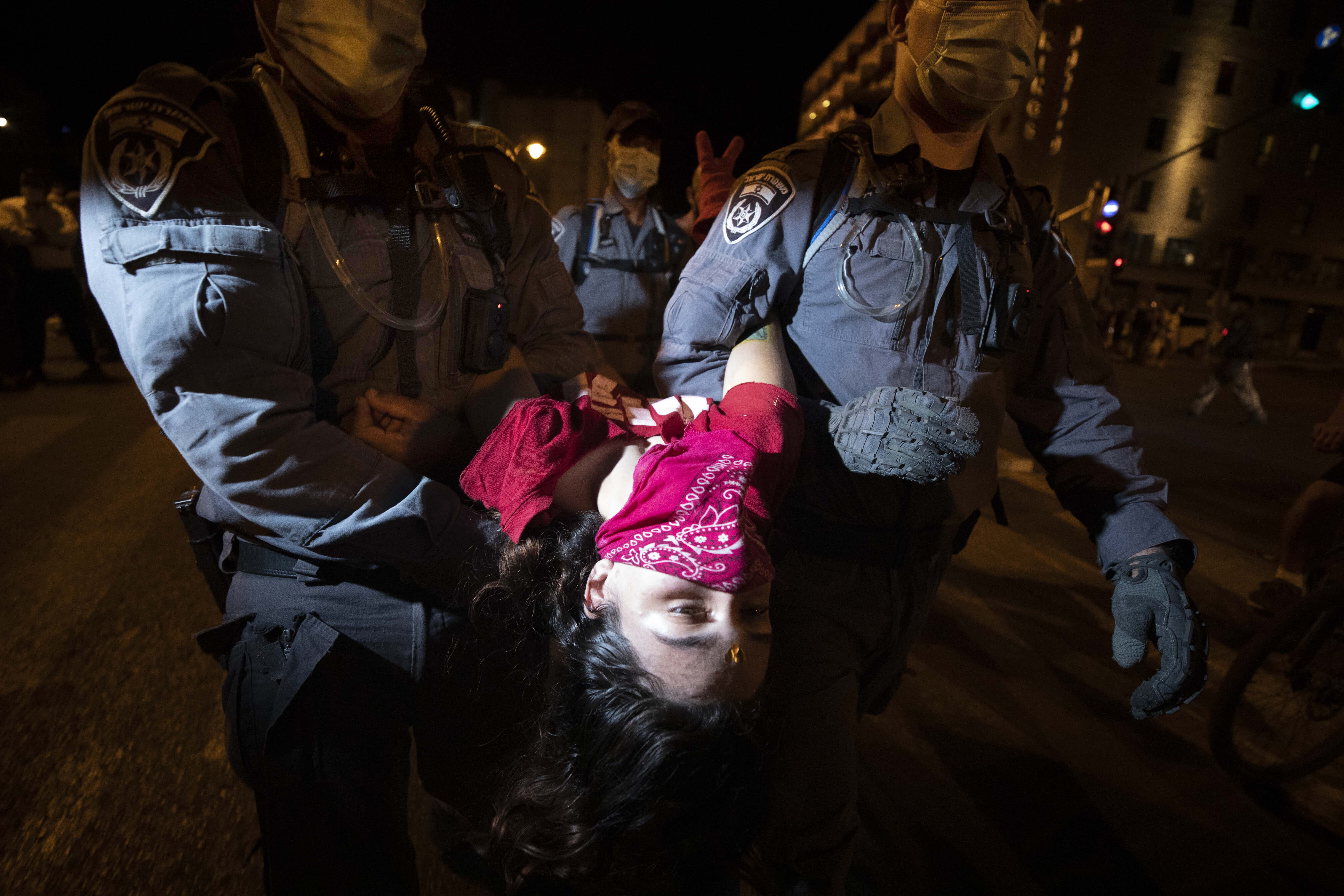 Police officers detain a protester during a demonstration against Prime Minister Benjamin Netanyahu outside his official residence in Jerusalem, Saturday, Sept. 12, 2020, demanding he resign over his trial on corruption charges and what is widely seen as his mishandling of the coronavirus pandemic. (AP Photo/Sebastian Scheiner)