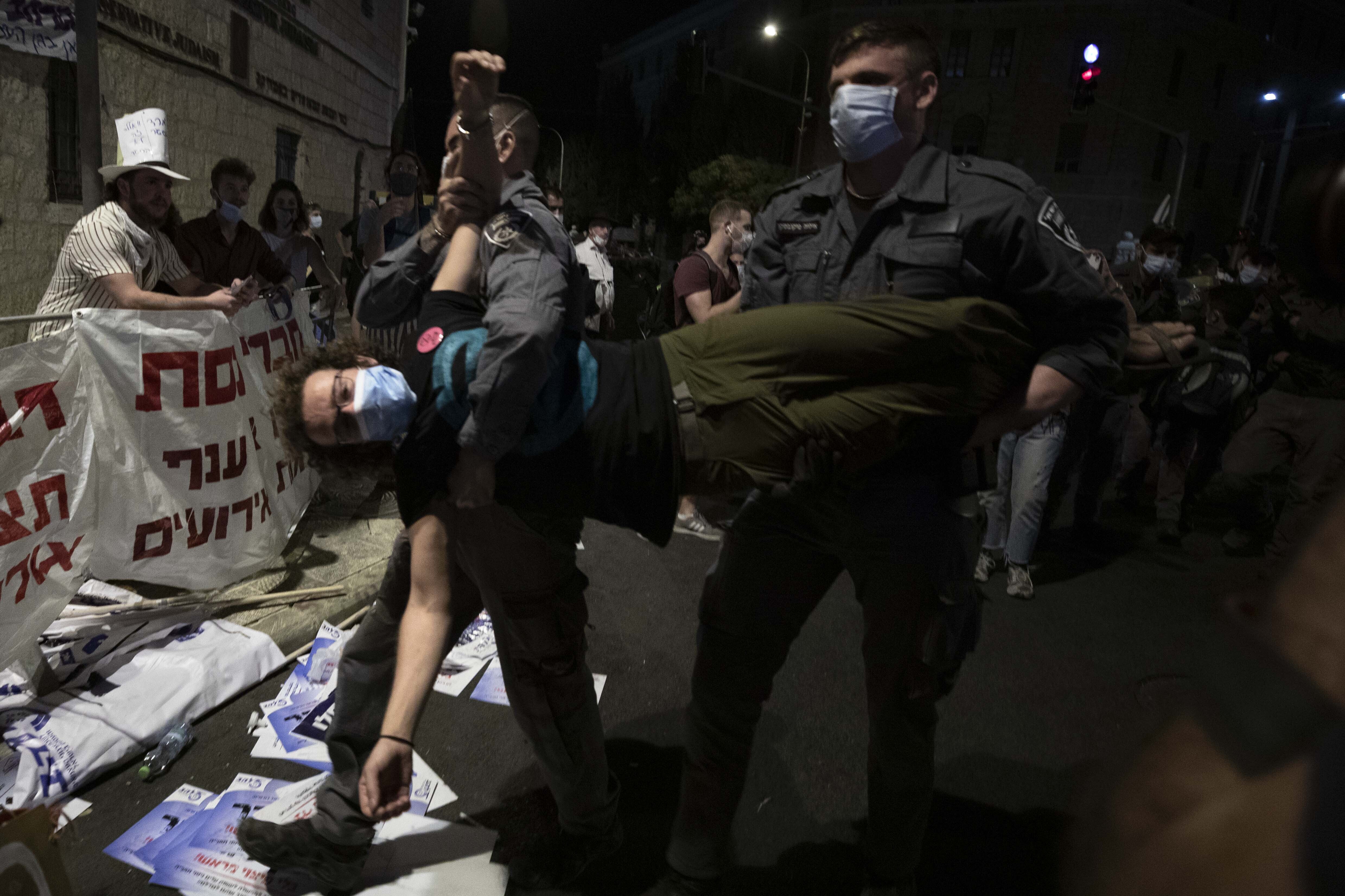 Police officers detain a protester during a demonstration against Prime Minister Benjamin Netanyahu outside his official residence in Jerusalem, Saturday, Sept. 12, 2020, demanding he resign over his trial on corruption charges and what is widely seen as his mishandling of the coronavirus pandemic. (AP Photo/Sebastian Scheiner)
