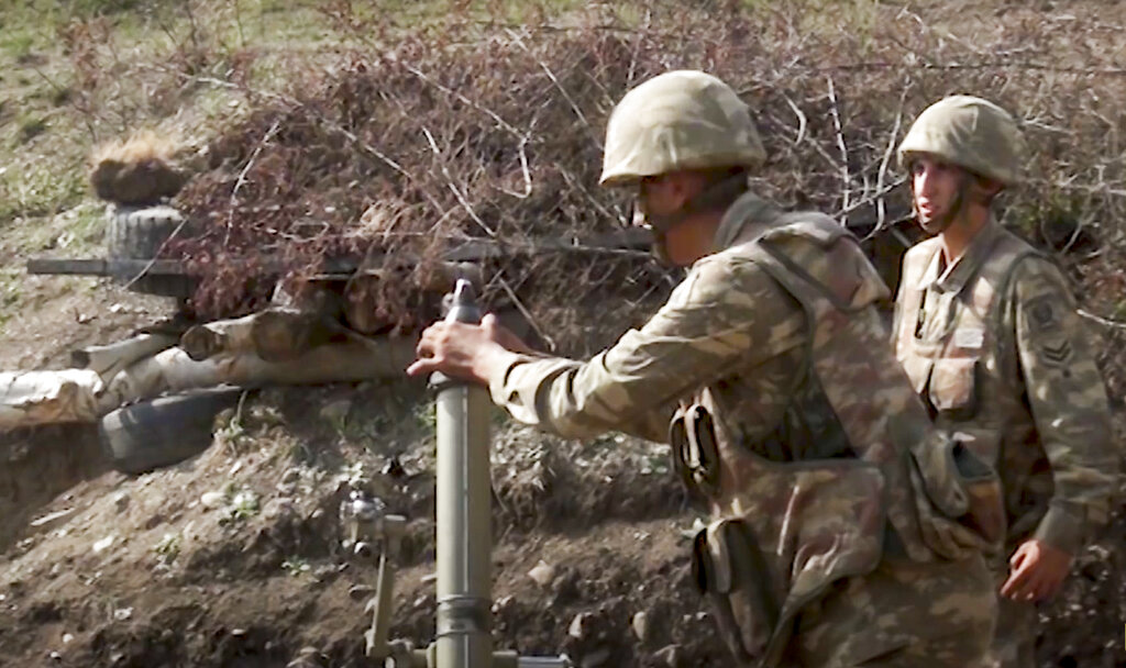 In this image taken from footage released by Azerbaijan's Defense Ministry on Sunday, Sept. 27, 2020, Azerbaijan's soldiers fire from a mortar at the contact line of the self-proclaimed Republic of Nagorno-Karabakh, Azerbaijan. Fighting between Armenian and Azerbaijani forces over the disputed separatist region of Nagorno-Karabakh continued on Monday morning after erupting the day before, with both sides blaming each other for resuming the attacks. (Azerbaijan's Defense Ministry via AP)
