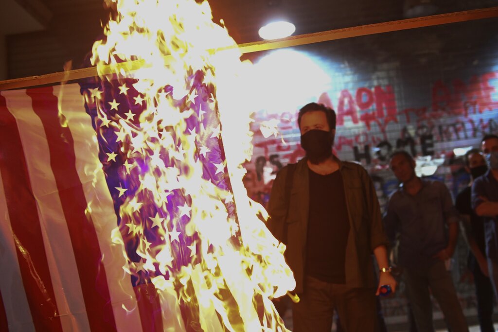 Protesters burn a US flag during a rally against the visit of the Secretary of State Mike Pompeo in Greece, outside the U.S. Consulate in the northern city of Thessaloniki, on Monday, Sept. 28, 2020. Pompeo said Monday that Washington will use its diplomatic and military influence in the region to try to ease a volatile dispute between NATO allies Greece and Turkey over energy rights in the eastern Mediterranean. (AP Photo/Giannis Papanikos)