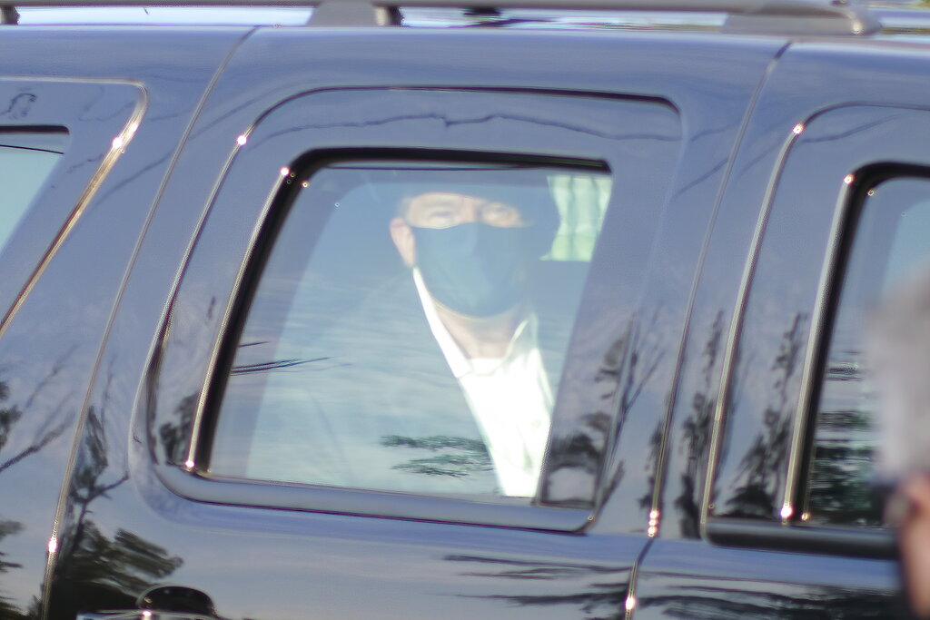 President Donald Trump drives past supporters gathered outside Walter Reed National Military Medical Center in Bethesda, Md., Sunday, Oct. 4, 2020. Trump was admitted to the hospital after contracting COVID-19. (AP Photo/Anthony Peltier)