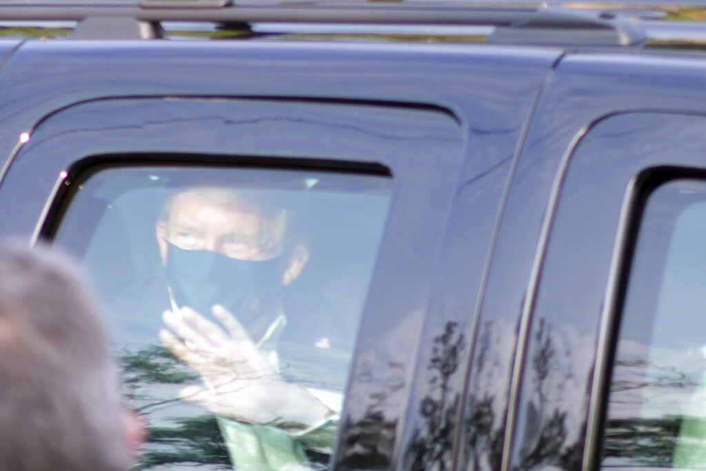 President Donald Trump drives past supporters gathered outside Walter Reed National Military Medical Center in Bethesda, Md., Sunday, Oct. 4, 2020. Trump was admitted to the hospital after contracting COVID-19. (AP Photo/Anthony Peltier)