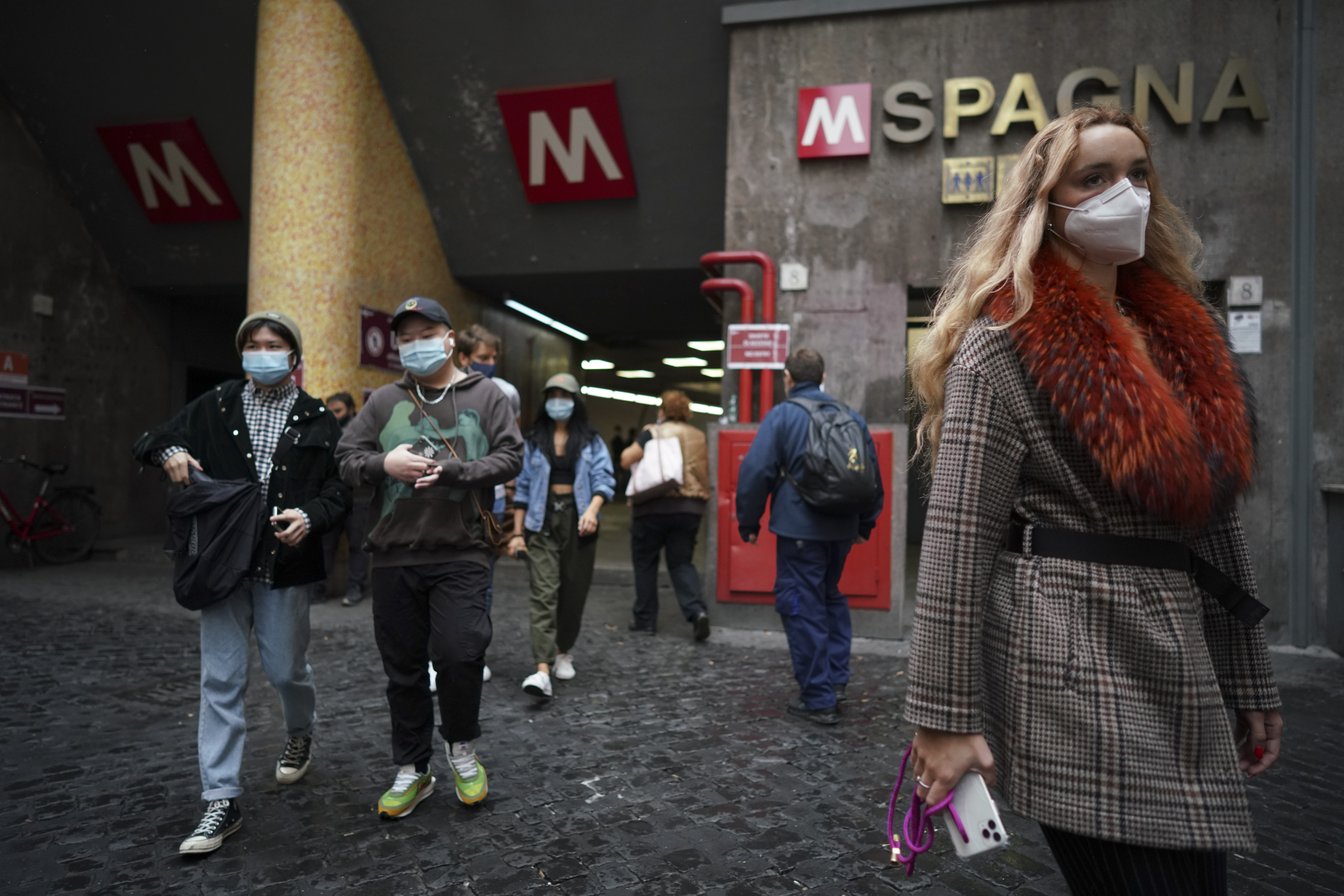 People wear face masks to prevent the spread of COVID-19 as they walk out of a subway station, in Rome, Saturday, Oct. 3, 2020. As of Saturday it is mandatory to wear masks outdoors in Lazio, the region that includes Rome. (AP Photo/Andrew Medichini)