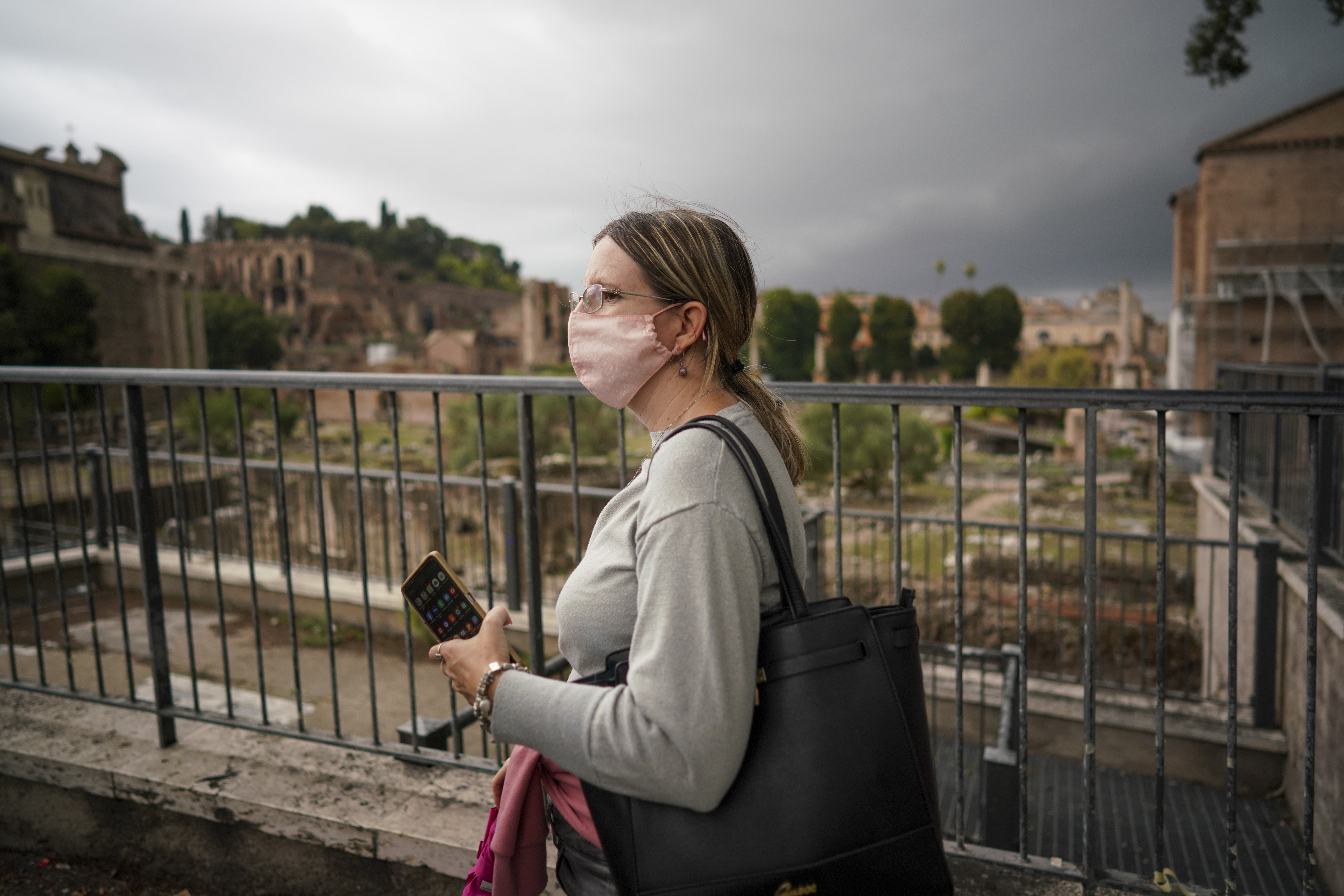 A woman wears a face mask to prevent the spread of COVID-19 as she walks by the ancient Roman Forum, in downtown Rome, Saturday, Oct. 3, 2020. As of Saturday it is mandatory to wear masks outdoors in Lazio, the region that includes Rome. (AP Photo/Andrew Medichini)