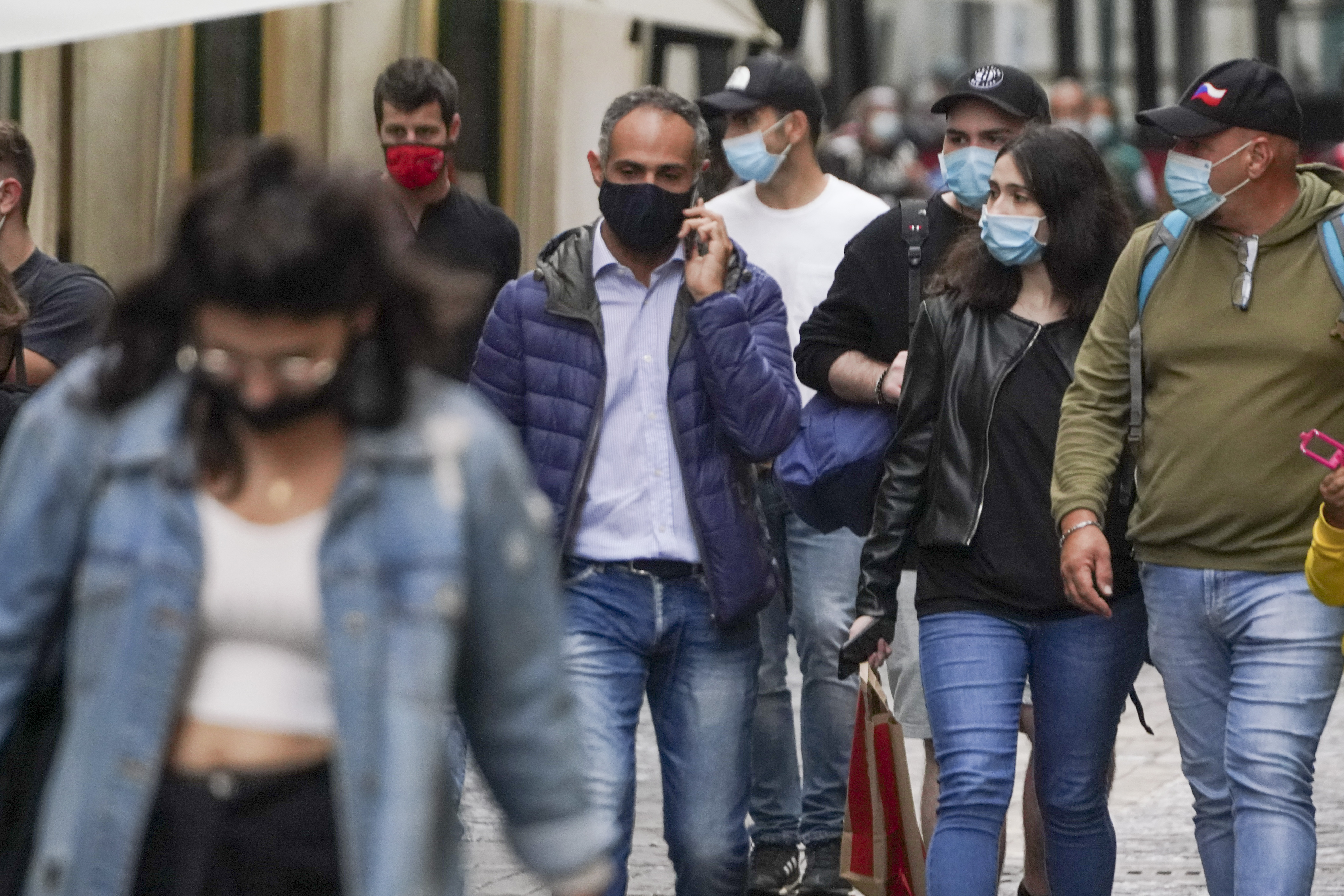People wear face masks to prevent the spread of COVID-19 as they stroll in downtown Rome, Saturday, Oct. 3, 2020. As of Saturday it is mandatory to wear masks outdoors in Lazio, the region that includes Rome. (AP Photo/Andrew Medichini)