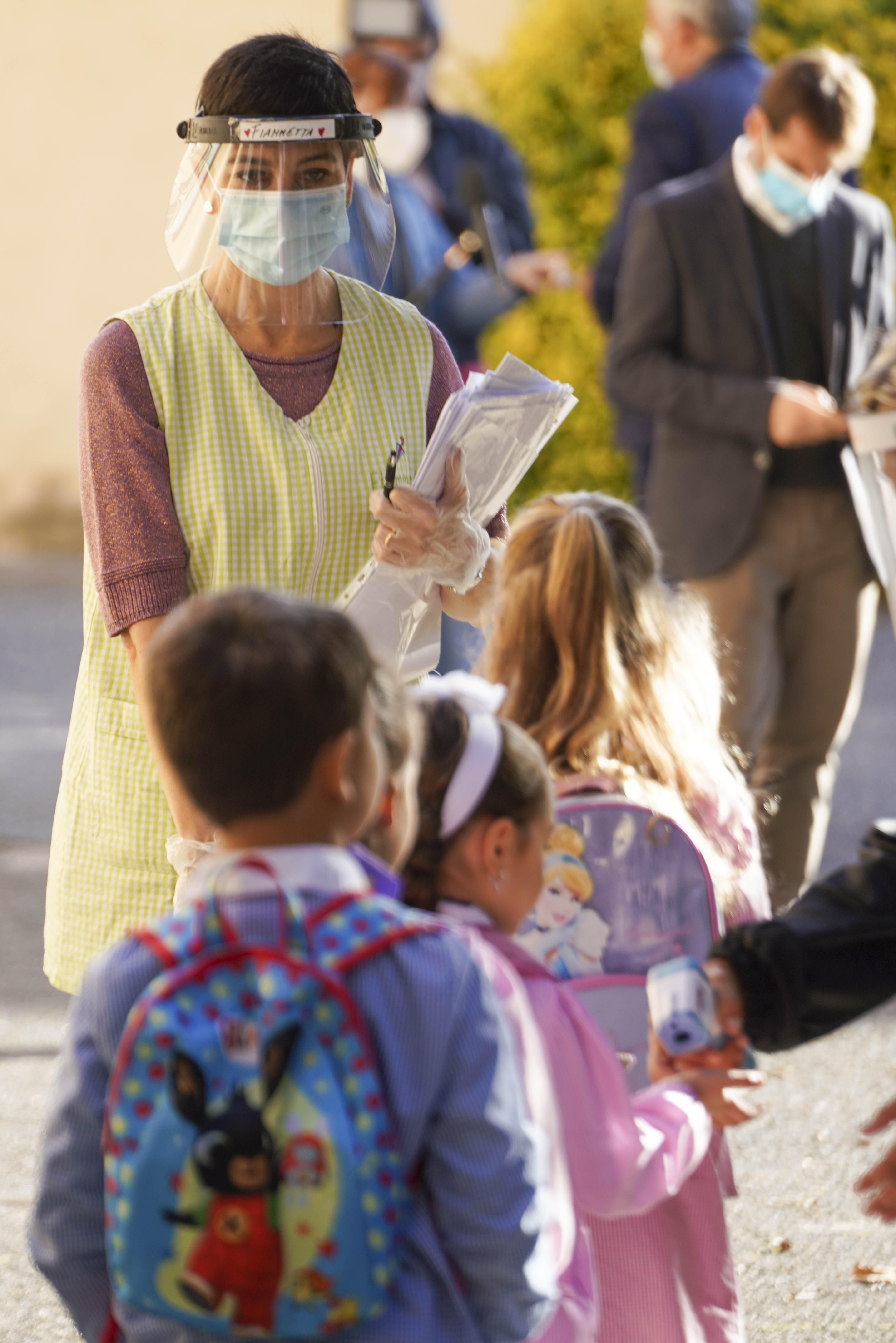 Medical personnel accompanies children to receive non-invasive Covid-19 tests with chewing gum, at the G.B. Grassi school, in Fiumicino, near Rome, Tuesday, Oct. 6, 2020. (AP Photo/Andrew Medichini)