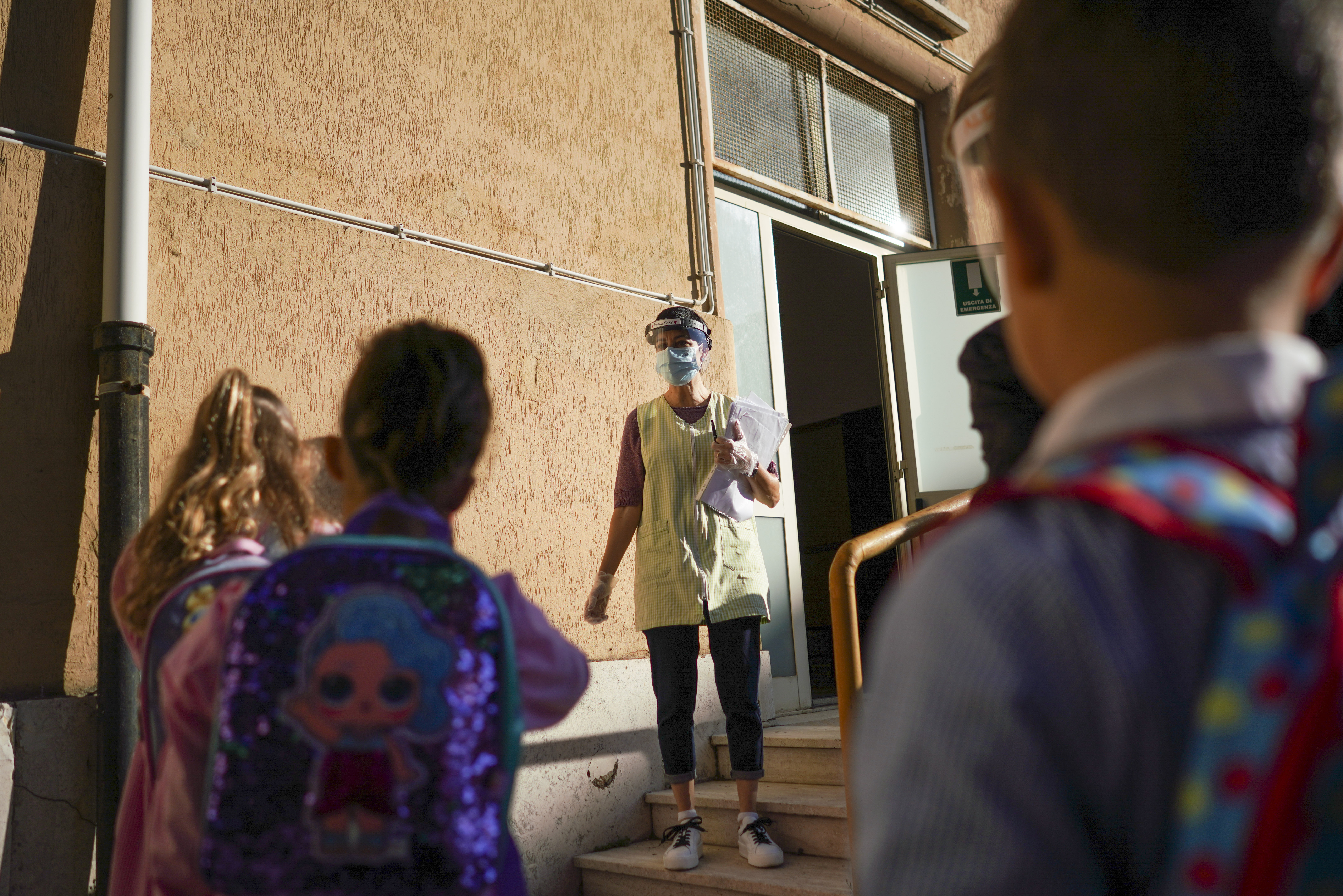 Medical personnel accompanies children to receive non-invasive Covid-19 tests with chewing gum, at the G.B. Grassi school, in Fiumicino, near Rome, Tuesday, Oct. 6, 2020. (AP Photo/Andrew Medichini)