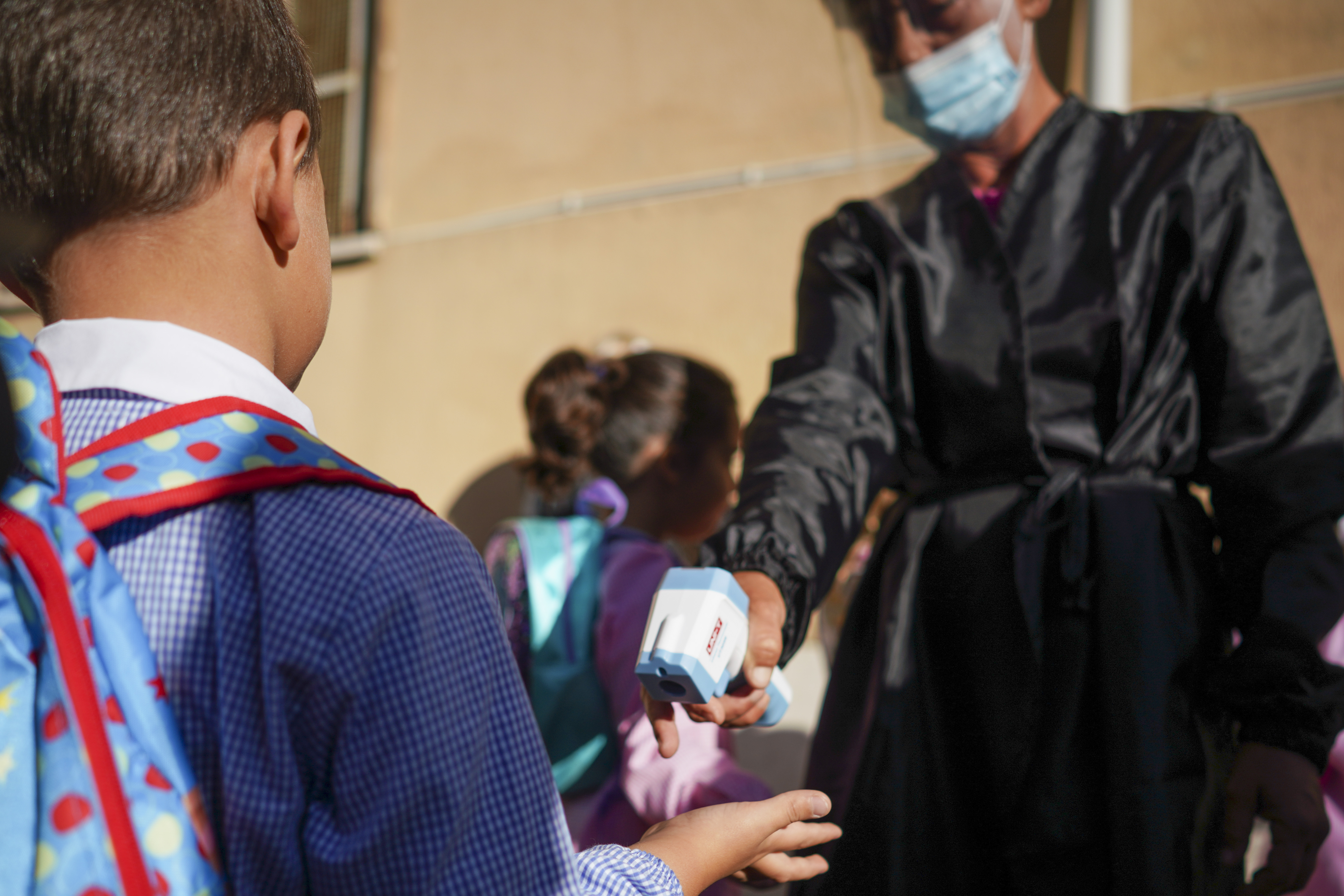 Medical personnel measures children' temperature as they are accompanied to receive non-invasive Covid 19 tests with chewing gum, at the G.B. Grassi school, in Fiumicino, near Rome, Tuesday, Oct. 6, 2020. (AP Photo/Andrew Medichini)