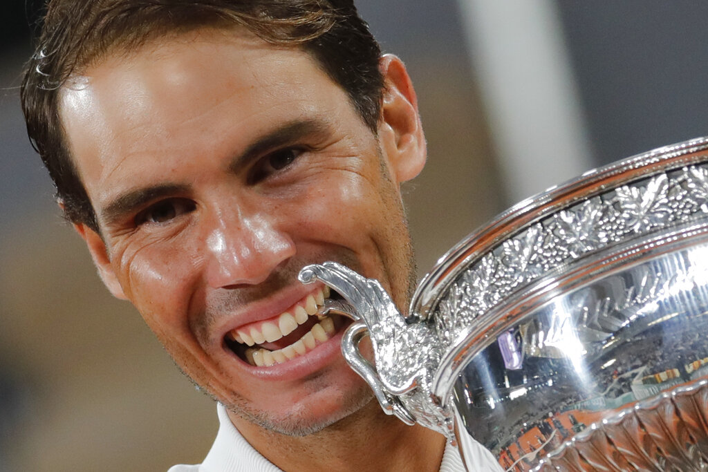Spain's Rafael Nadal bites the trophy as he celebrates winning the final match of the French Open tennis tournament against Serbia's Novak Djokovic in three sets, 6-0, 6-2, 7-5, at the Roland Garros stadium in Paris, France, Sunday, Oct. 11, 2020. (AP Photo/Christophe Ena)