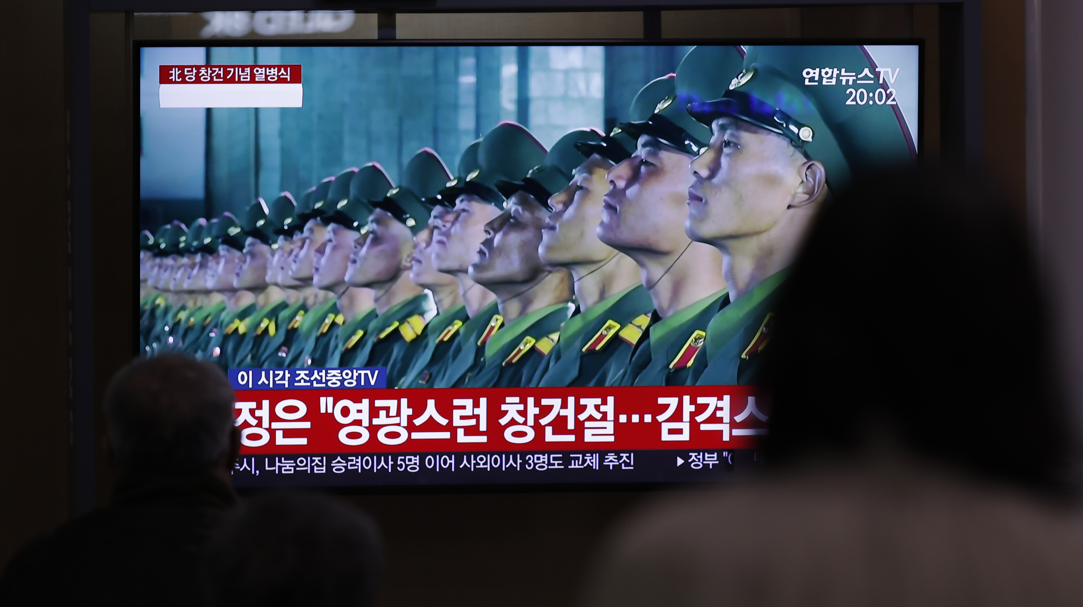 People wearing face masks watch a TV screen during a news program reporting about the ceremony to mark the 75th founding anniversary of the North Korea's ruling Workers' party, at the Seoul Railway Station in Seoul, South Korea, Saturday, Oct. 10, 2020. A part of letters read on the top 