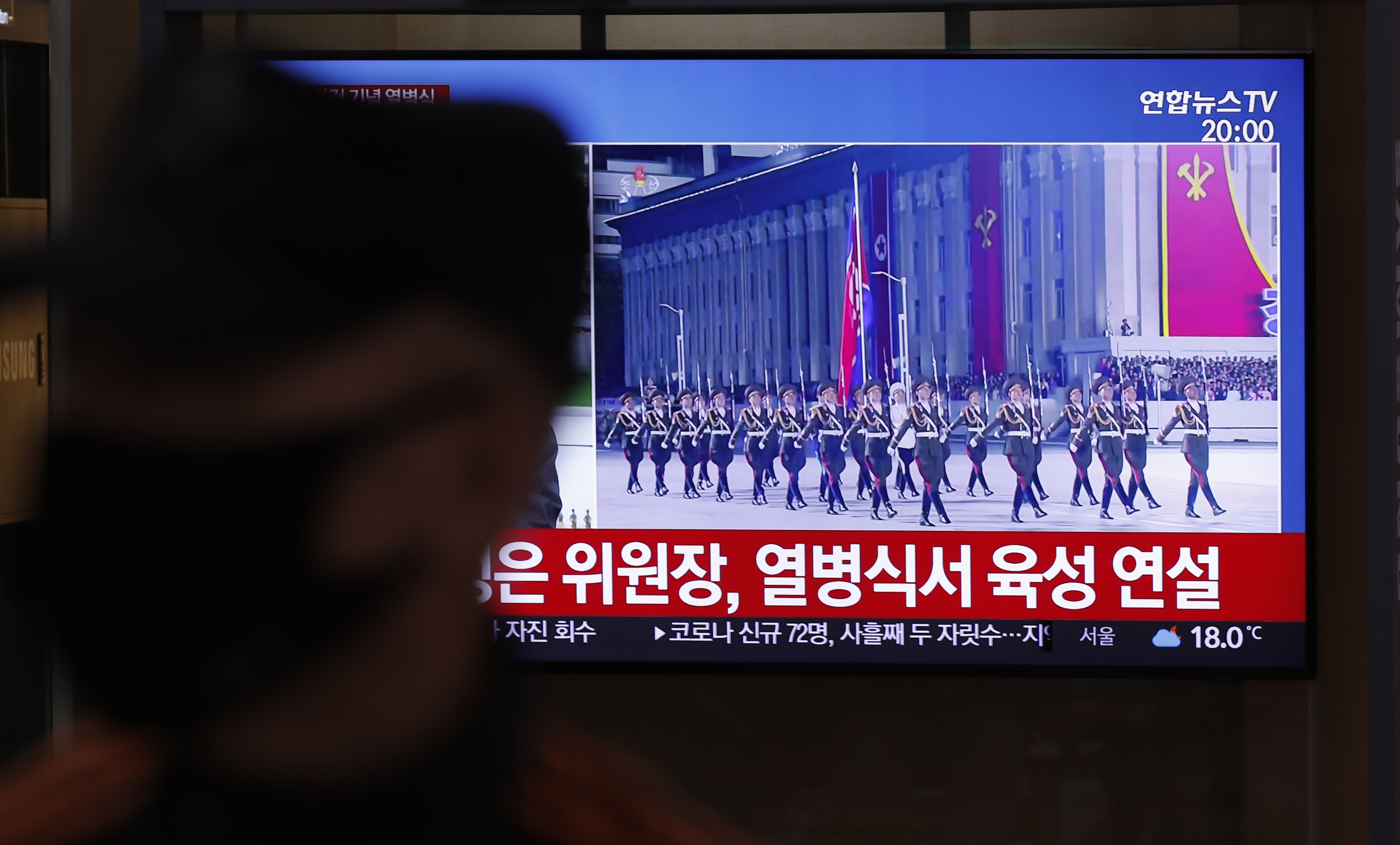 A man wearing a face mask walks near a TV screen during a news program reporting about the ceremony to mark the 75th founding anniversary of the North Korea's ruling Workers' party, at the Seoul Railway Station in Seoul, South Korea, Saturday, Oct. 10, 2020. A part of letters read 