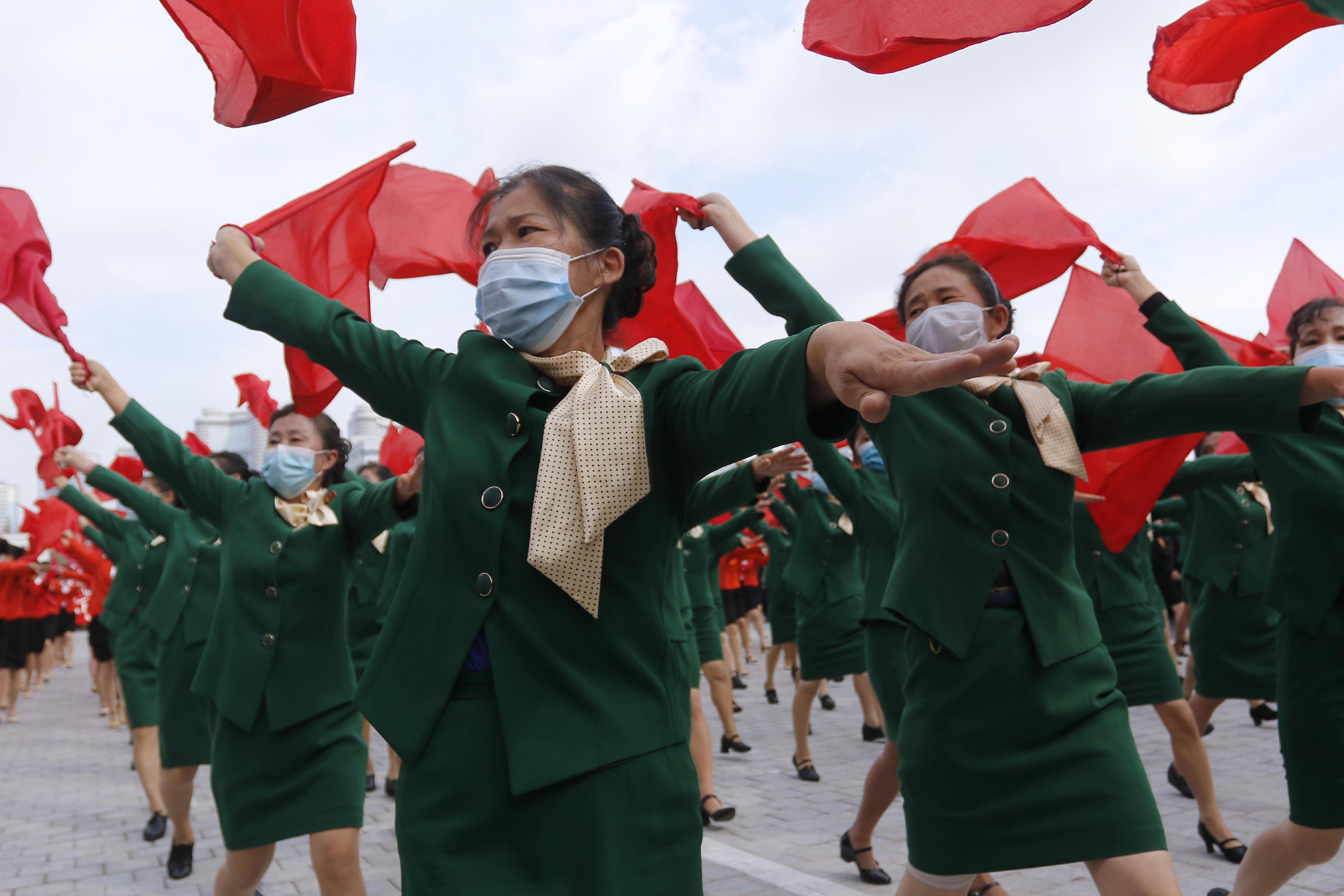Women wearing face masks to help curb the spread of the coronavirus parade with flags during a rally to welcome the 8th Congress of the Workers' Party of Korea at Kim Il Sung Square in Pyongyang, North Korea, Monday, Oct. 12, 2020. (AP Photo/Jon Chol Jin)