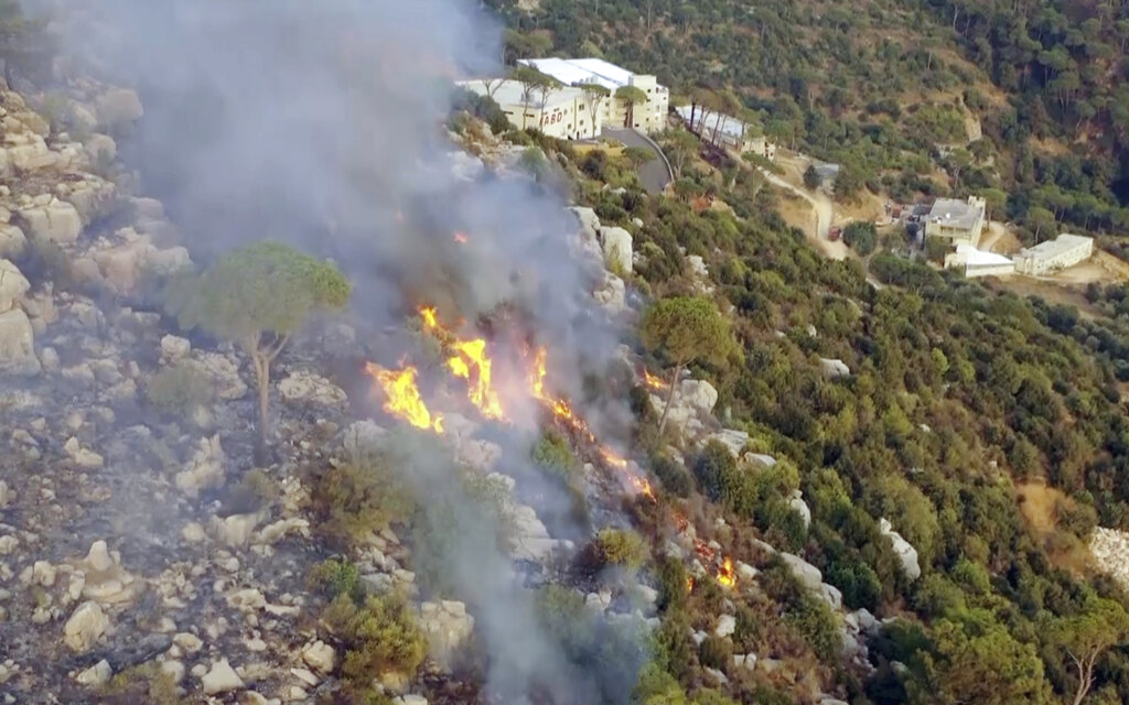 In this frame grab from video, flames rise at the scene of forest fire in Ras el-Harf village, in the Baabda district, Lebanon, Friday, Oct. 9, 2020. Wildfires around the Middle East triggered by a heatwave hitting the region have killed two people, forced thousands of people to leave their homes and detonated landmines along the Lebanon-Israel border, state media and officials said Saturday. (AP Photo)