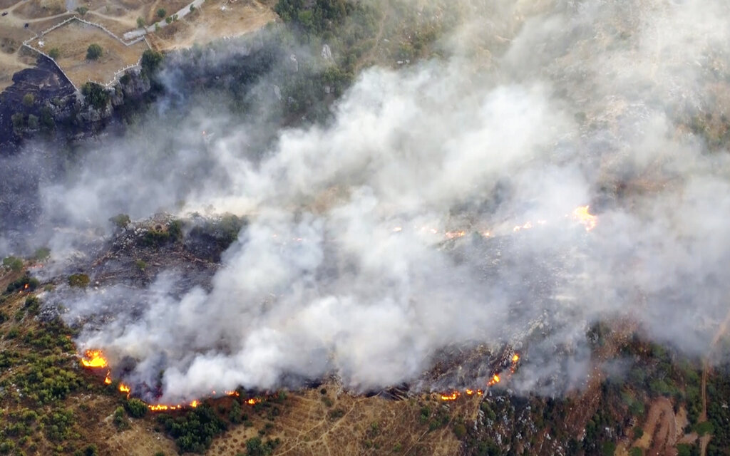 In this frame grab from video, flames rise at the scene of forest fire in Ras el-Harf village, in the Baabda district, Lebanon, Friday, Oct. 9, 2020. Wildfires around the Middle East triggered by a heatwave hitting the region have killed two people, forced thousands of people to leave their homes and detonated landmines along the Lebanon-Israel border, state media and officials said Saturday. (AP Photo)