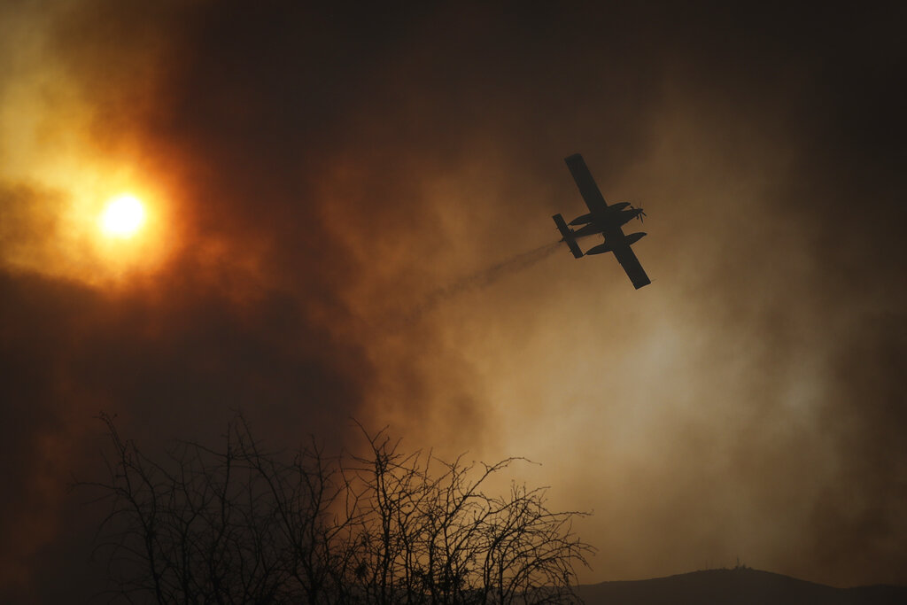 A plane drops water on fires in Cordoba, Argentina, Monday, Oct. 12, 2020. Wildfires have destroyed thousands of hectares in the Argentine province of Cordoba this year, amid a drought and high temperatures.  (AP Photo/Nicolas Aguilera)