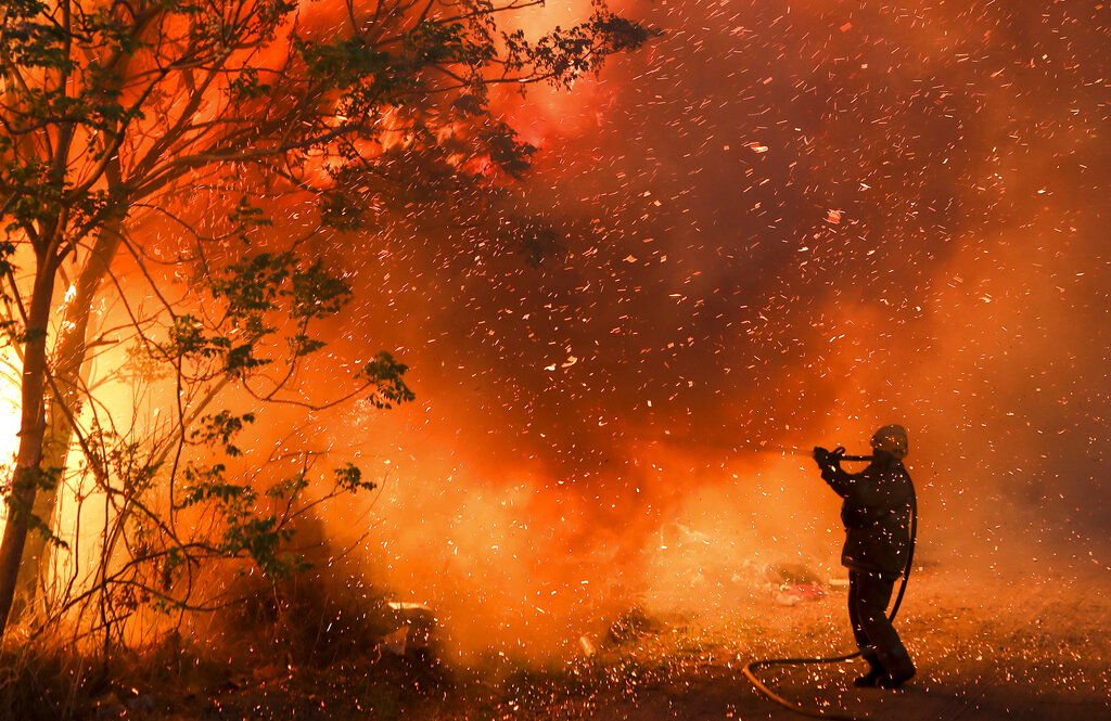 A firefighter battles flames in Cordoba, Argentina, Monday, Oct. 12, 2020. Wildfires have destroyed thousands of hectares in the Argentine province of Cordoba this year, amid a drought and high temperatures. (AP Photo/Nicolas Aguilera)