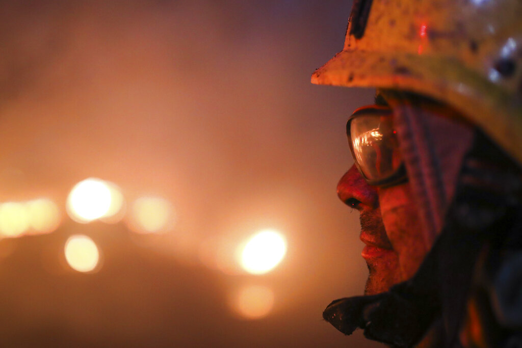 A firefighter looks at flames in Cordoba, Argentina, Monday, Oct. 12, 2020. Wildfires have destroyed thousands of hectares in the Argentine province of Cordoba this year, amid a drought and high temperatures. (AP Photo/Nicolas Aguilera)