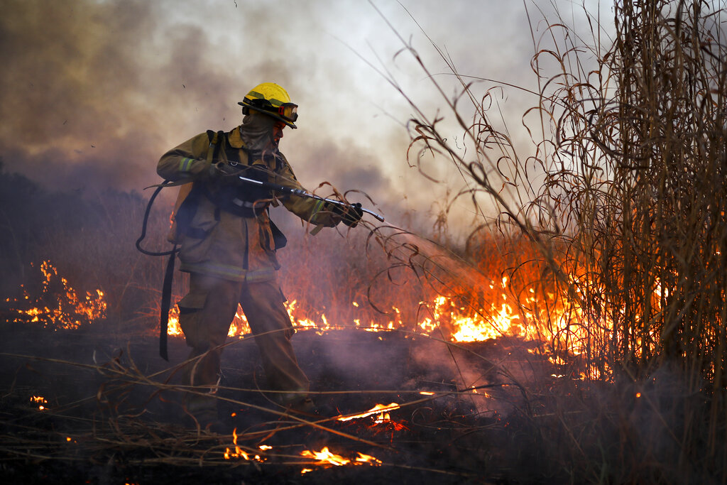 A fireman works to put out a fire in Cordoba, Argentina, Monday, Oct. 12, 2020. Wildfires have destroyed thousands of hectares in the Argentine province of Cordoba this year, amid a drought and high temperatures. (AP Photo/Nicolas Aguilera)
