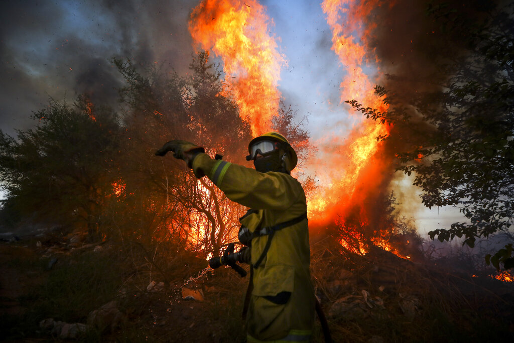 A firefighter battles a fire in Cordoba, Argentina, Monday, Oct. 12, 2020. The Cordoba province has reported nearly 50,000 hectares in fires since the beginning of the year amid high temperatures and strong winds. (AP Photo/Nicolas Aguilera)