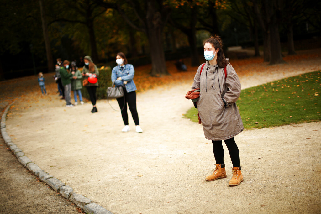 People, wearing masks and keeping social distance to prevent the spread of the coronavirus, wait in line to be tested in a Red Cross COVID-19 test center at Cinquantenaire park in Brussels, Monday, Oct. 19, 2020. Bars and restaurants across Belgium shut down for a month and a night-time curfew entered into force Monday in the hard-hit coronavirus country as health authorities warned of a possible sanitary 