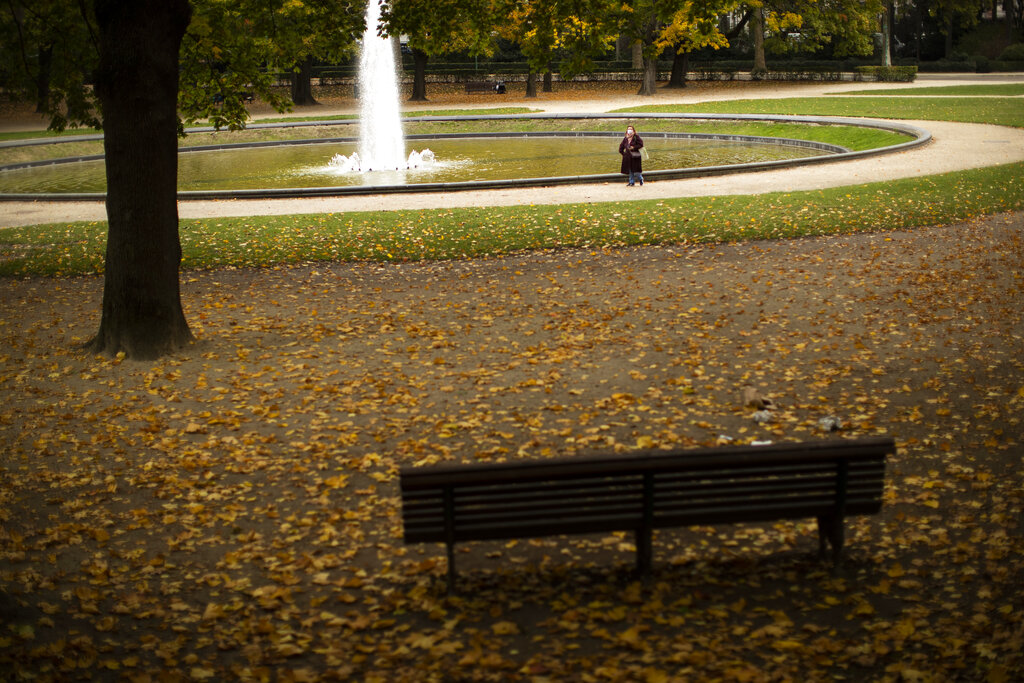 A woman, wearing a face mask to prevent the spread of the coronavirus, walks along Cinquantenaire park in Brussels, Tuesday, Oct. 20, 2020. Bars and restaurants across Belgium shut down for a month and a night-time curfew entered into force Monday in the hard-hit coronavirus country as health authorities warned of a possible sanitary “tsunami.