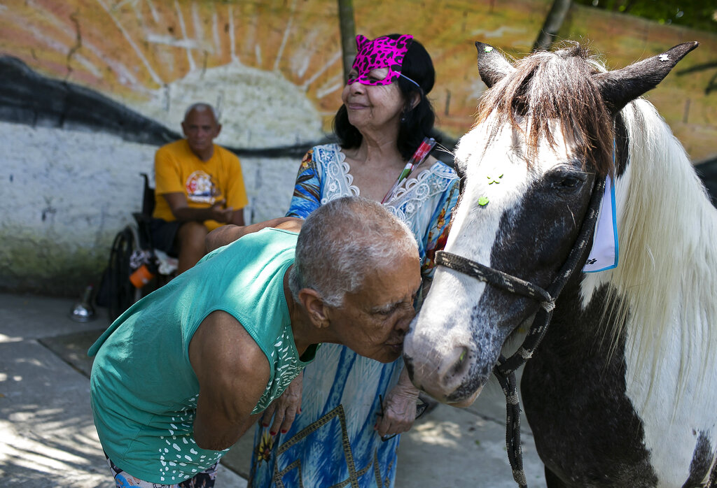 An elderly person kisses a horse named Tony at the 