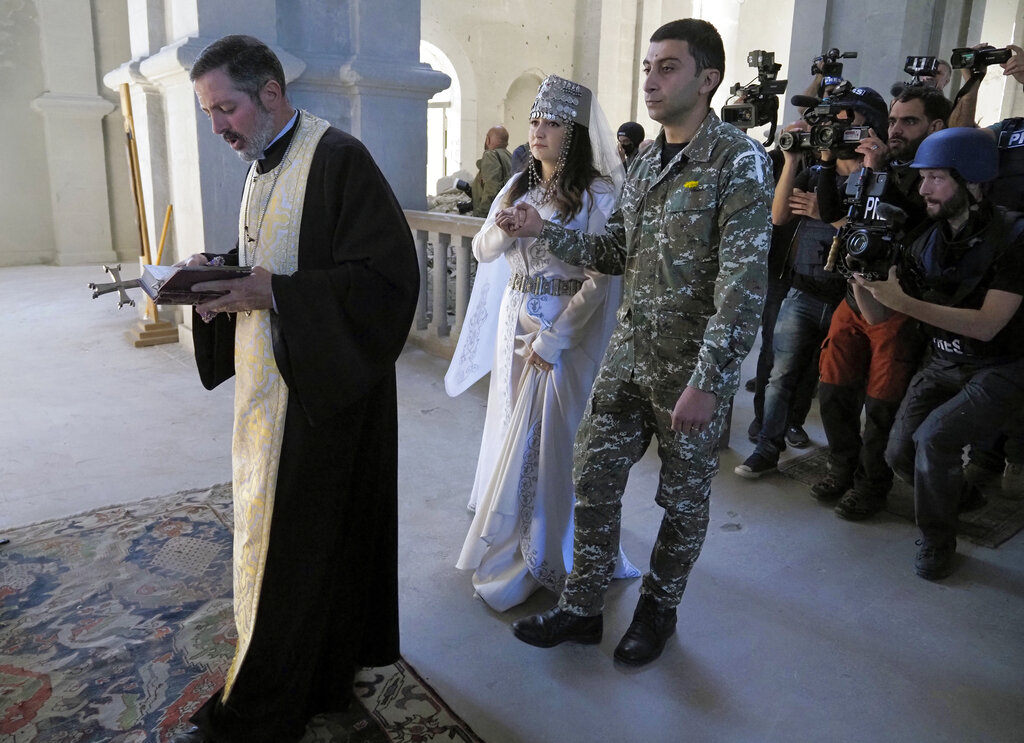 Newlyweds, soldier Hovhannes Hovsepyan, right, and Mariam Sargsyan get married in the Holy Savior Cathedral, damaged by shelling by Azerbaijan's artillery during a military conflict in Shushi, the separatist region of Nagorno-Karabakh, Saturday, Oct. 24, 2020. The wedding was celebrated even as intense fighting in the region has continued. (AP Photo)