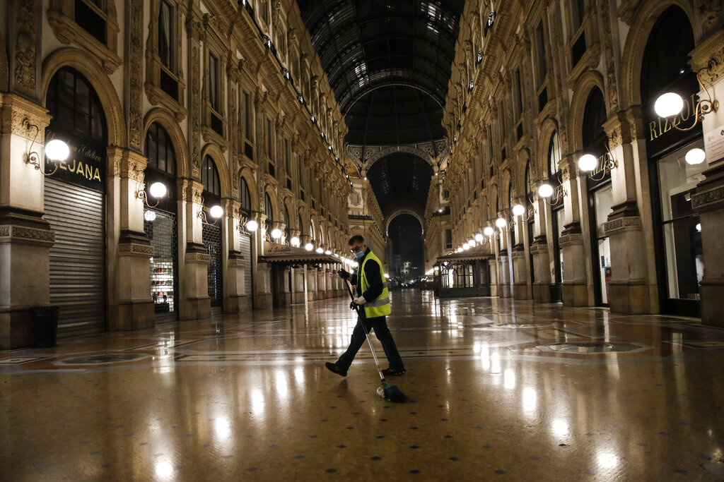 A cleaner sweeps in an empty Vittorio Emanuele II arcarde, in Milan, northern Italy, early Sunday, Oct. 25, 2020. Since the 11 p.m.-5 a.m. curfew took effect last Thursday, people can only move around during those hours for reasons of work, health or necessity. (AP Photo/Luca Bruno)