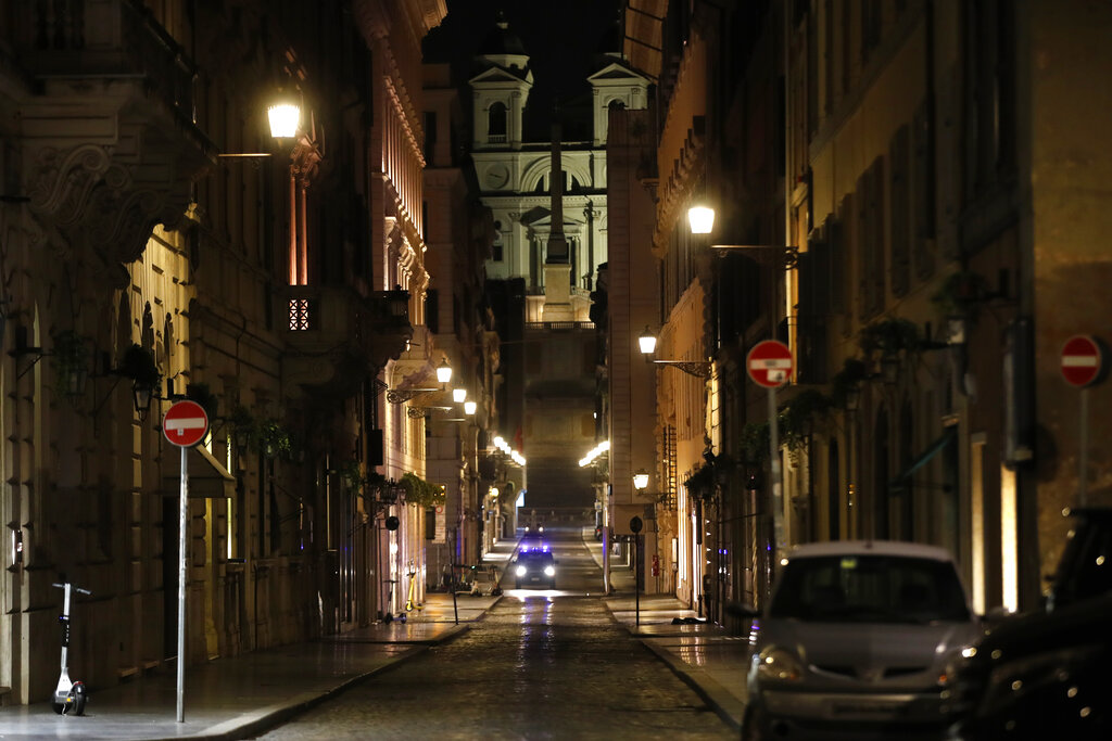 An Italian Carabinieri paramilitary police car patrols an empty street leading to the Spanish Steps and Trinita' dei Monti Church Rome, early Monday, Oct. 26, 2020. Since an 11 p.m.-5 a.m. curfew took effect Friday, people can only move around during those hours for reasons of work, health or necessity. (AP Photo/Alessandra Tarantino)