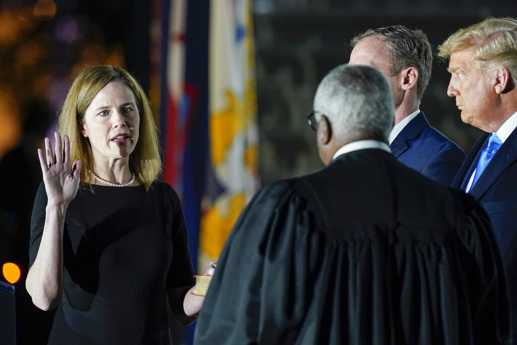 President Donald Trump watches as Supreme Court Justice Clarence Thomas administers the Constitutional Oath to Amy Coney Barrett on the South Lawn of the White House White House in Washington, Monday, Oct. 26, 2020, after Barrett was confirmed to be a Supreme Court justice by the Senate earlier in the evening. Holding the Bible is Barrett's husband, Jesse Barrett. (AP Photo/Patrick Semansky)