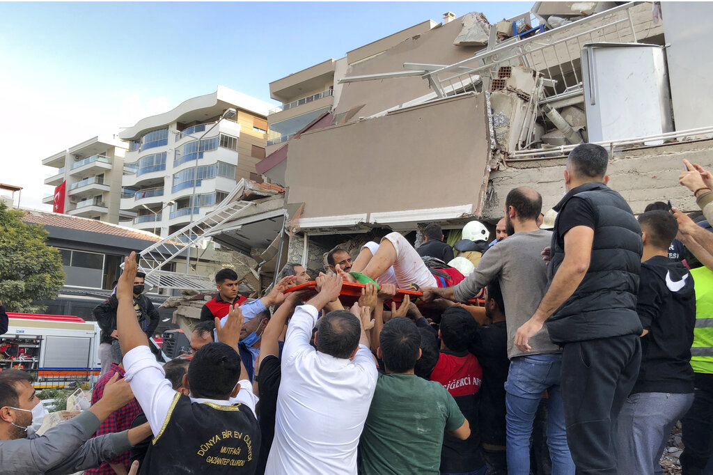 Rescue workers and local people carry a wounded person found in the debris of a collapsed building, in Izmir, Turkey, Friday, Oct. 30, 2020, after a strong earthquake in the Aegean Sea has shaken Turkey and Greece. Turkey's Disaster and Emergency Management Presidency said Friday's earthquake was centered in the Aegean at a depth of 16,5 kilometers (10.3 miles) and registered at a 6.6 magnitude.(AP Photo/Ismail Gokmen)