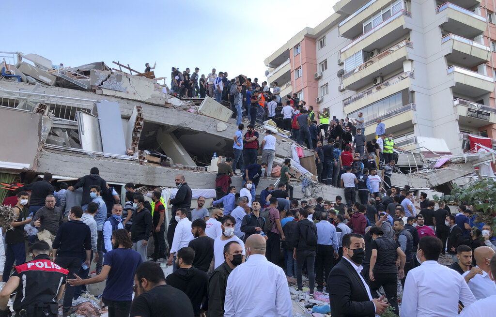Rescue workers and local people try to save residents trapped in the debris of a collapsed building, in Izmir, Turkey, Friday, Oct. 30, 2020. A strong earthquake struck Friday in the Aegean Sea between the Turkish coast and the Greek island of Samos, collapsing buildings in the city of Izmir in western Turkey, and officials said at least six people were killed and scores were injured.(AP Photo/Ismail Gokmen)