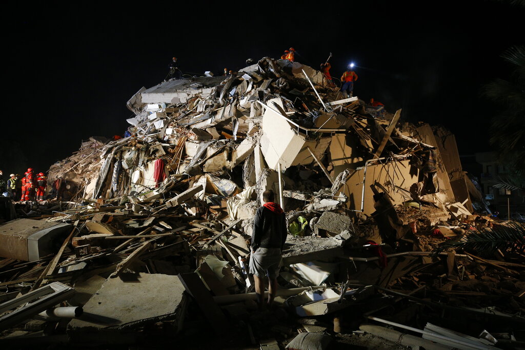 Members of rescue services search in the debris of a collapsed building for survivors in Izmir, Turkey, early Saturday, Oct. 31, 2020. A strong earthquake struck Friday in the Aegean Sea between the Turkish coast and the Greek island of Samos, killing several people and injuring hundreds amid collapsed buildings and flooding. (AP Photo/Emrah Gurel)