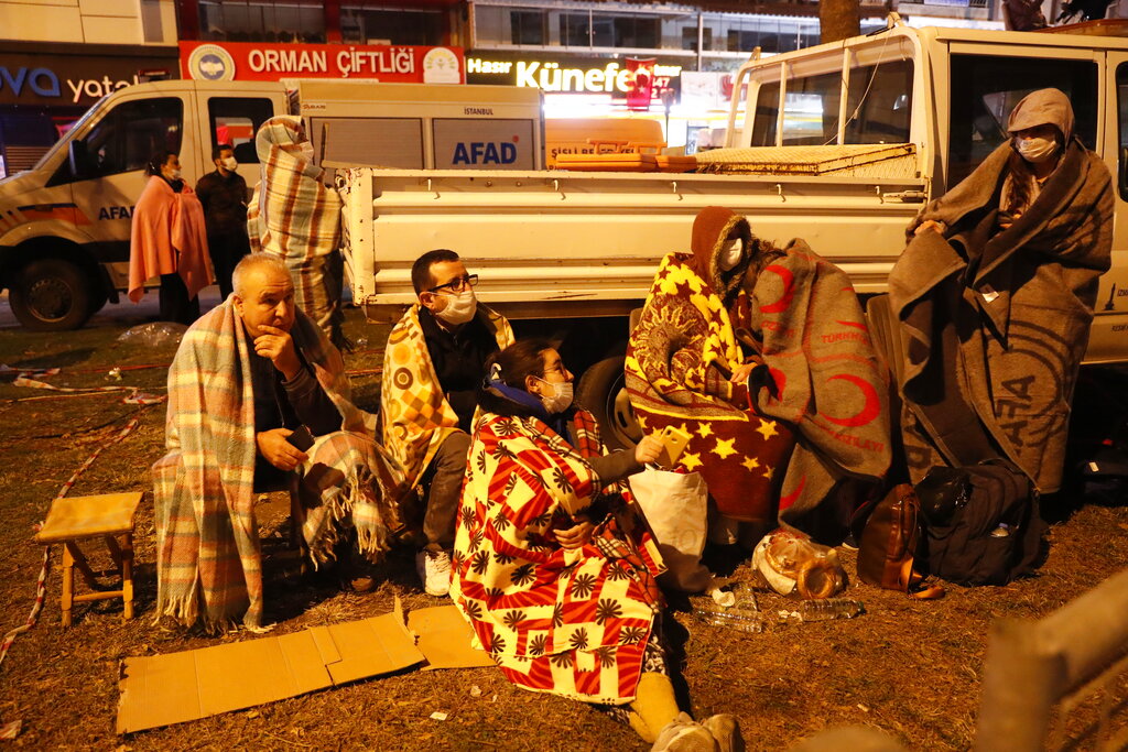 Local residents, staying outdoors for fear of aftershocks, watch members of rescue services searching for survivors in the debris of a collapsed building in Izmir, Turkey, early Saturday, Oct. 31, 2020. Rescue teams on Saturday ploughed through concrete blocs and debris of eight collapsed buildings in Turkey's third largest city in search of survivors of a powerful earthquake that struck Turkey's Aegean coast and north of the Greek island of Samos, killing dozens and injured scores of others. (AP Photo/Darko Bandic)