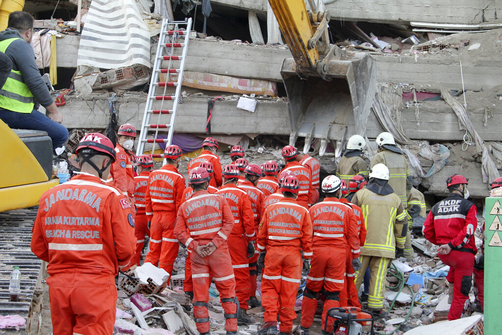 Rescue workers try to rescue residents trapped in debris of a collapsed building, in Izmir, Turkey, Saturday, Oct. 31, 2020. Rescue teams on Saturday plowed through concrete blocs and debris of eight collapsed buildings in search of survivors of a powerful earthquake that struck Turkey's Aegean coast and north of the Greek island of Samos. (AP Photo/Ismail Gokmen)