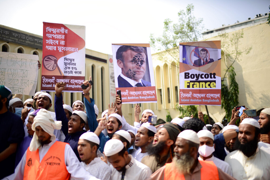 Supporters of Islami Andolan Bangladesh, an Islamist political party, hold posters of French President Emmanuel Macron as they protest against the publishing of caricatures of the Prophet Muhammad they deem blasphemous, in Dhaka, Bangladesh, Tuesday, Oct. 27, 2020. Muslims in the Middle East and beyond on Monday called for boycotts of French products and for protests over the caricatures, but Macron has vowed his country will not back down from its secular ideals and defense of free speech. Poster reads 