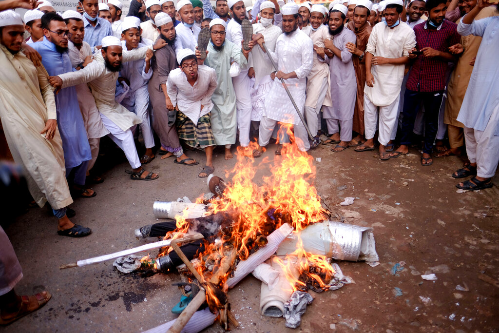 Supporters of Islami Oikya Jote, an Islamist political party, burn an effigy representing French President Emmanuel Macron during a protest against the publishing of caricatures of the Prophet Muhammad they deem blasphemous, in Dhaka, Bangladesh, Wednesday, Oct. 28, 2020. Muslims in the Middle East and beyond on Monday called for boycotts of French products and for protests over the caricatures, but Macron has vowed his country will not back down from its secular ideals and defense of free speech. Posters read 