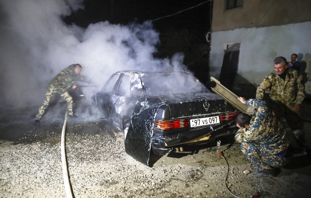 Firefighters extinguish a burning car after shelling by Azerbaijan's artillery during a military conflict in Stepanakert, the separatist region of Nagorno-Karabakh, Tuesday, Nov. 3, 2020.  The heavy fighting involving heavy artillery, rockets and drones has raged despite repeated international attempts to end hostilities. (AP Photo)