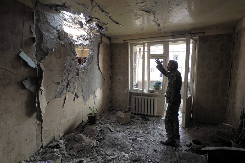 A man gestures in an apartment damaged by shelling by Azerbaijan's artillery during a military conflict in Stepanakert, the separatist region of Nagorno-Karabakh, Tuesday, Nov. 3, 2020. Fighting over the separatist territory of Nagorno-Karabakh entered sixth week on Sunday, with Armenian and Azerbaijani forces blaming each other for new attacks. (AP Photo)